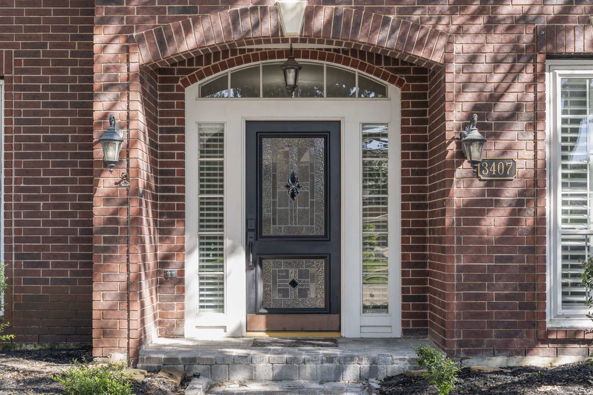A gorgeous custom wood and leaded glass front door with sidelights and an arched transom window welcomes guests inside.