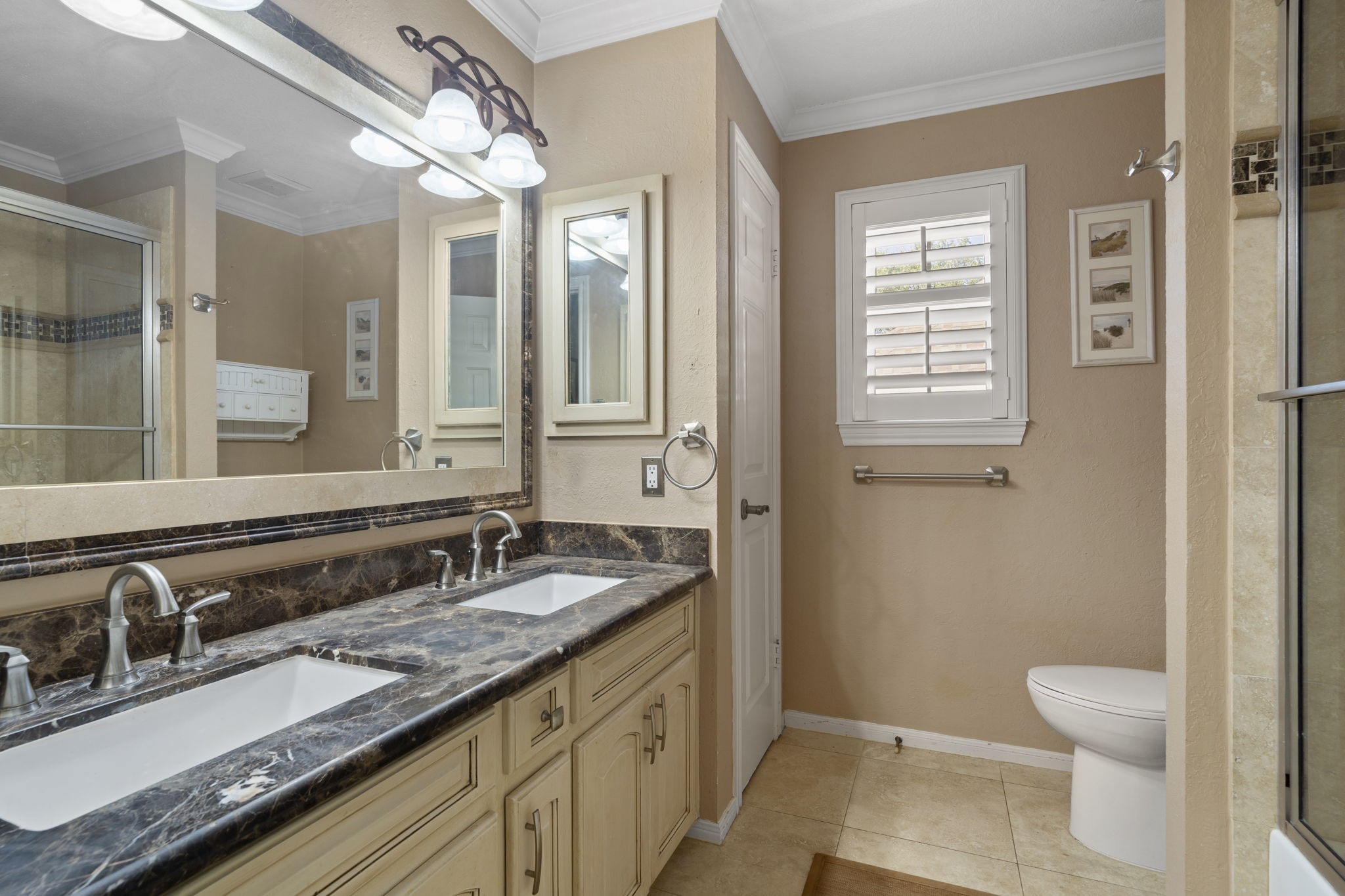 This spacious bathroom is designed for convenience, featuring a dual vanity that allows two to get ready at once, along with a shower/tub combo and a linen closet for added storage.