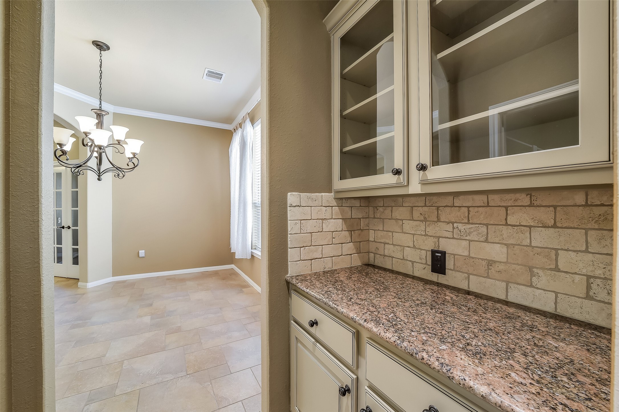 Granite counter and stone backsplash dress up this butler's pantry. Glass front cabinets display your favorite crystal or serving pieces.