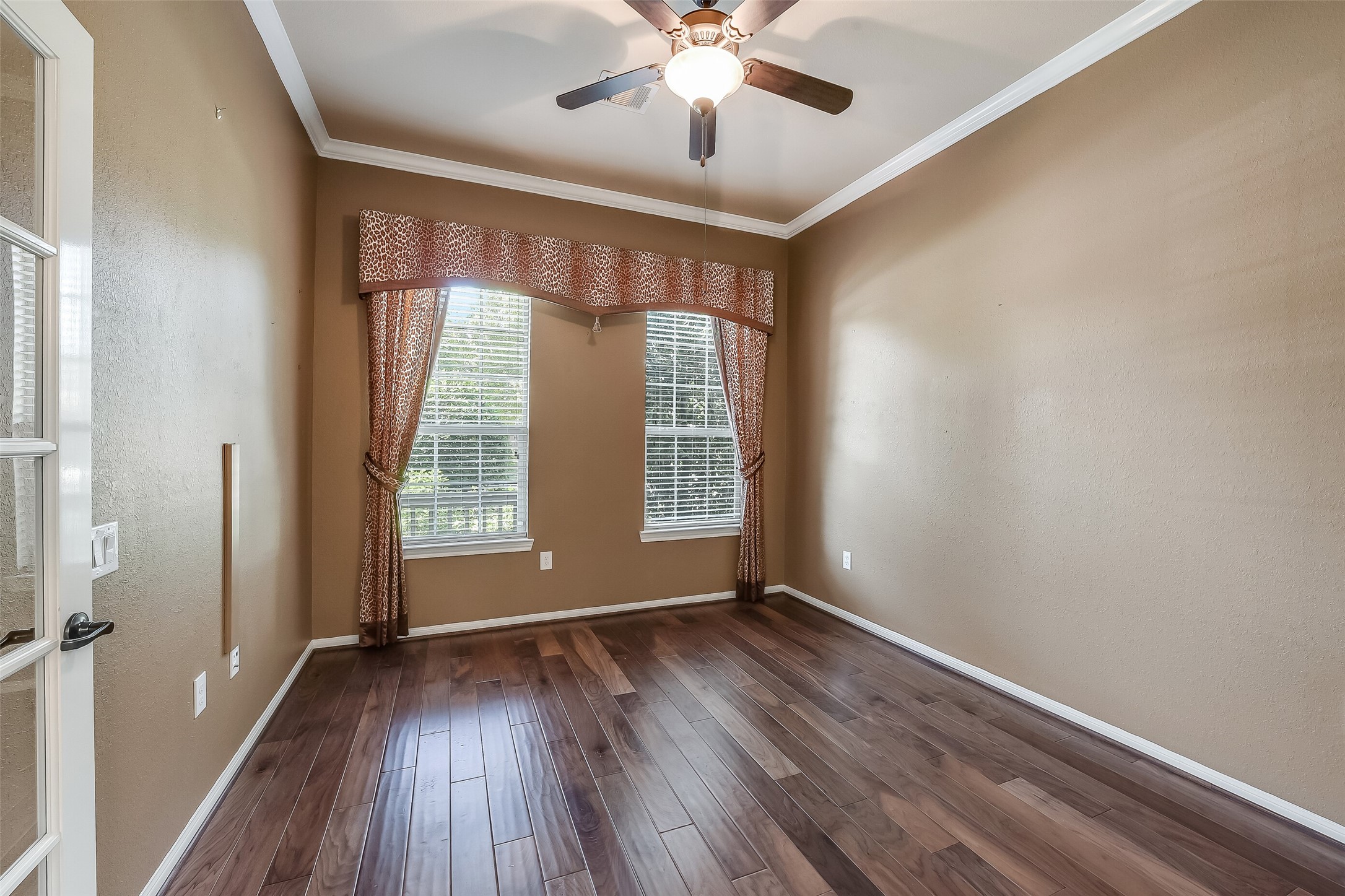 Study boasts rich hardwood flooring, custom window dressing, and crown moulding.