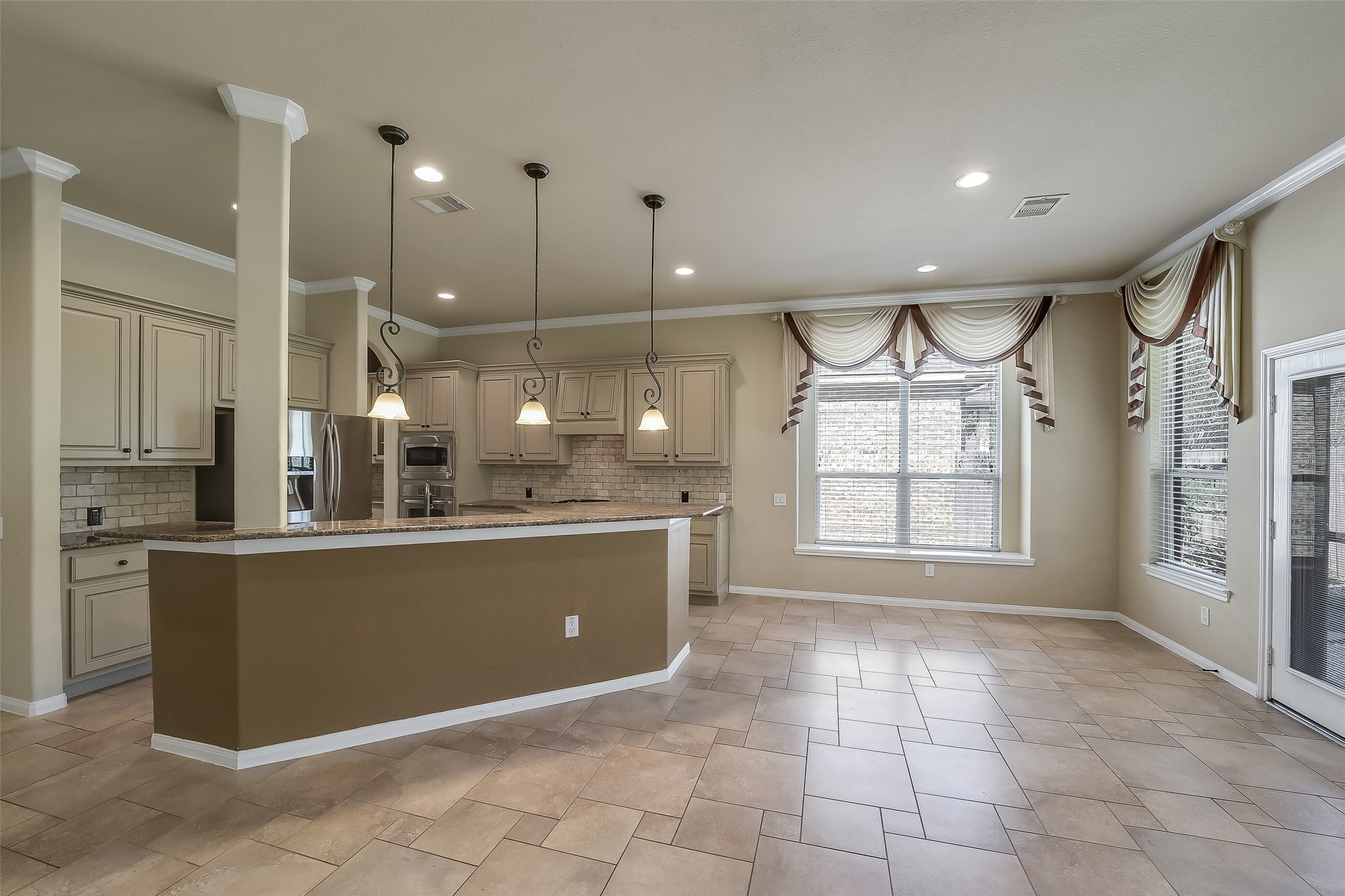 The long breakfast bar overlooks the family room. Notice the beautiful pattern in the extended tile flooring. This home is even more beautiful in person.