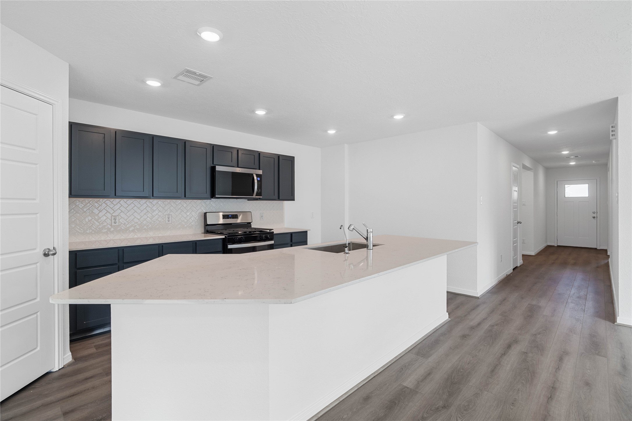 The central kitchen island features a durable quartz countertop, an undermount stainless steel sink, with a Moen faucet. The kitchen island has additional storage space, increased counter and prep space, and is the social hub of the home--where family and guests gather and interact!