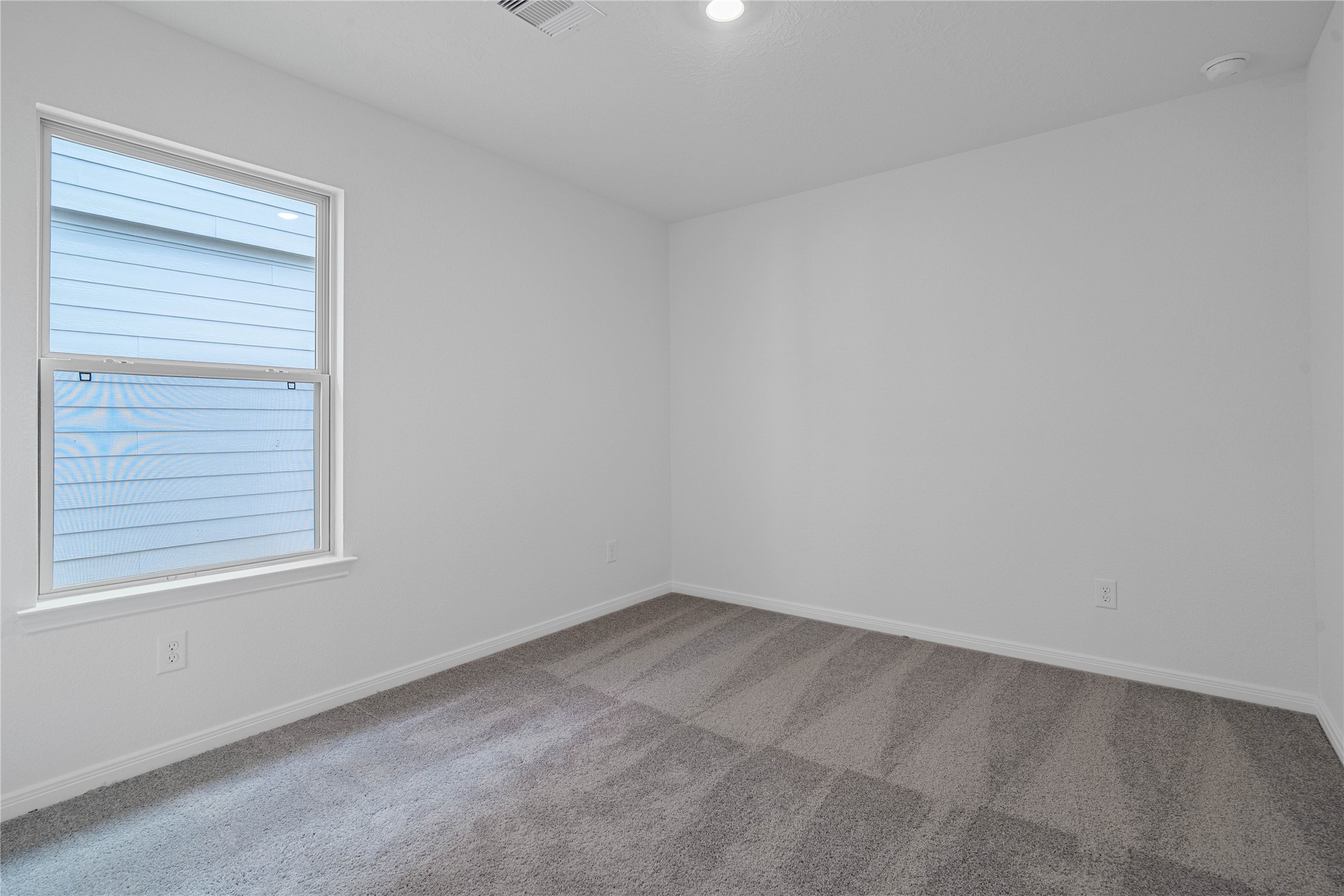 Light-filled secondary bedroom complete with cozy carpet flooring, ample closet space, and a large window.