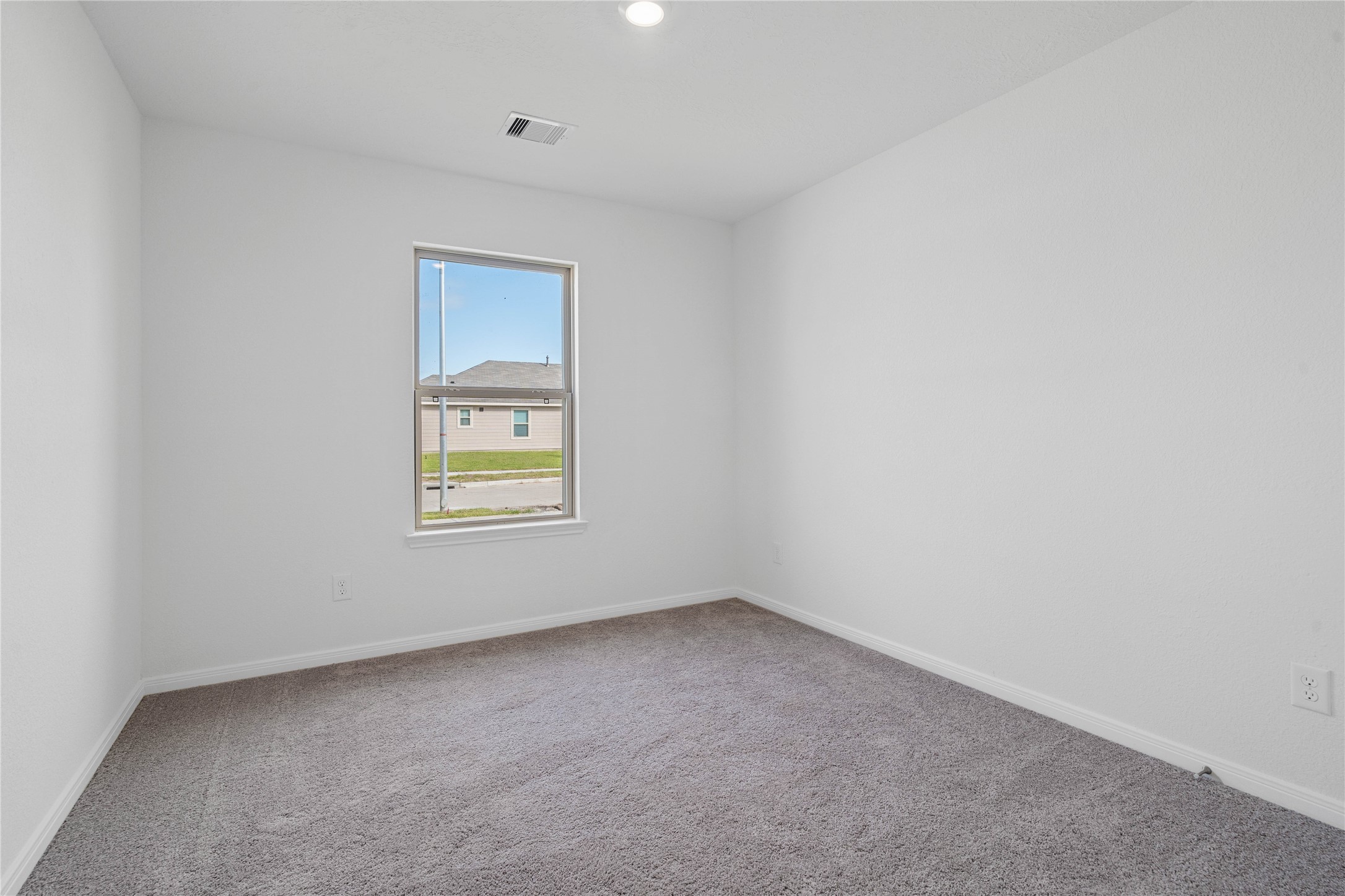 Tucked peacefully in the front of the home is this secondary bedroom. It features plush carpet flooring, large window, and closet space.