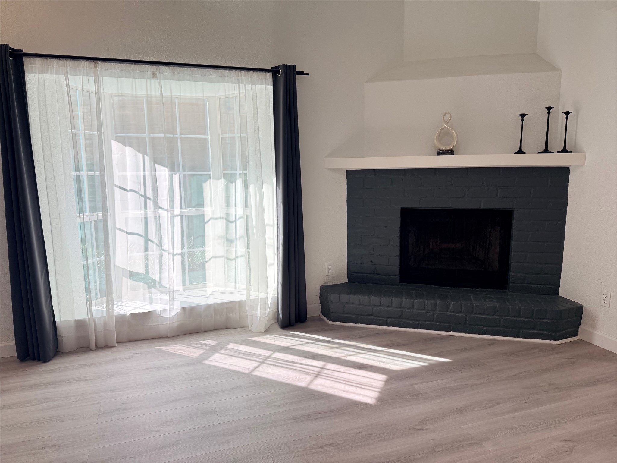 View of the corner wood burning fireplace and awesome bay window bringing in the natural light!