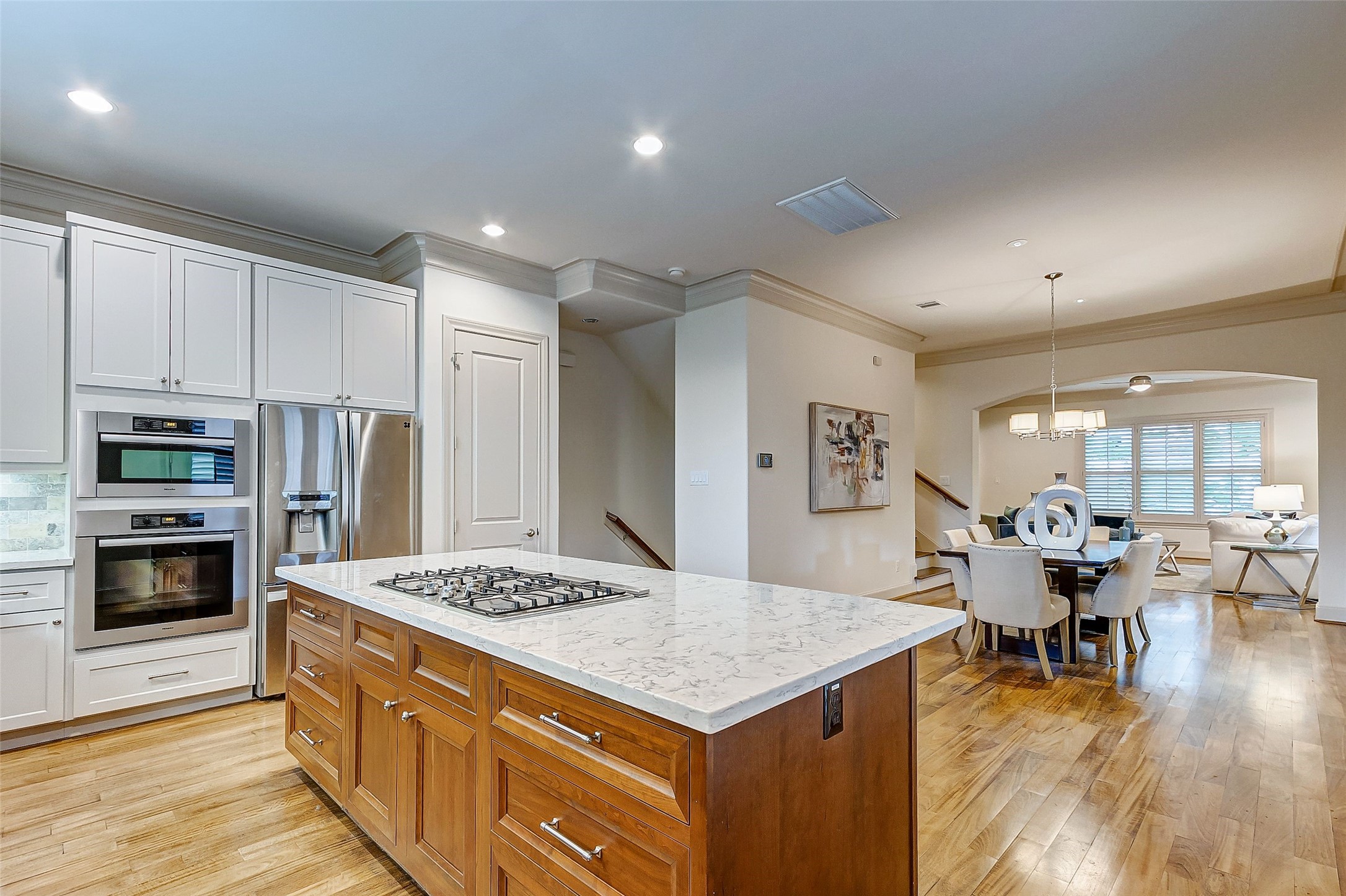 Elevate your entertaining in this stunning home, showcasing a large, modern kitchen with stainless steel appliances and sleek wood flooring.