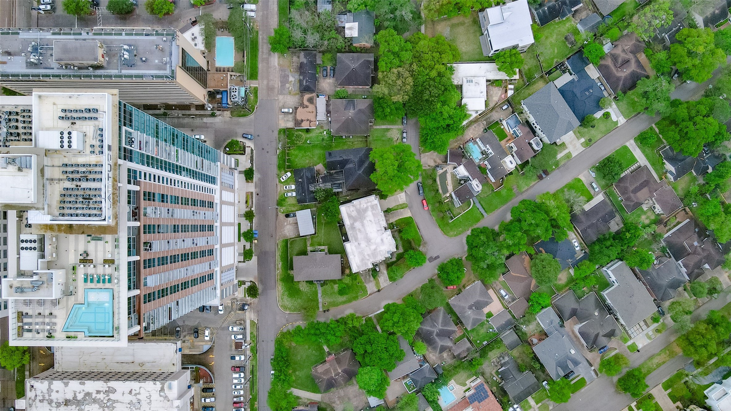 Aerial view showcasing a vibrant neighborhood with a blend of modern high-rise buildings and charming residential homes, surrounded by lush greenery.
