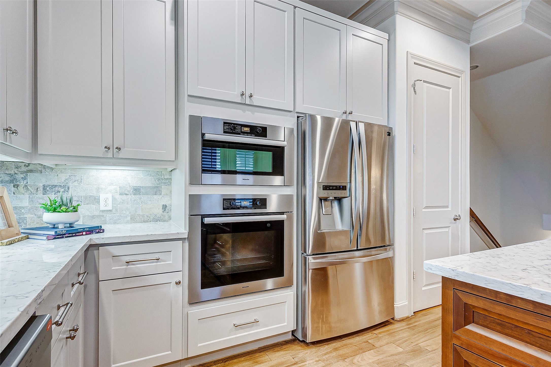 Sleek modern kitchen featuring stainless steel appliances, elegant white cabinetry, and a stylish marble countertop for a sophisticated cooking space.