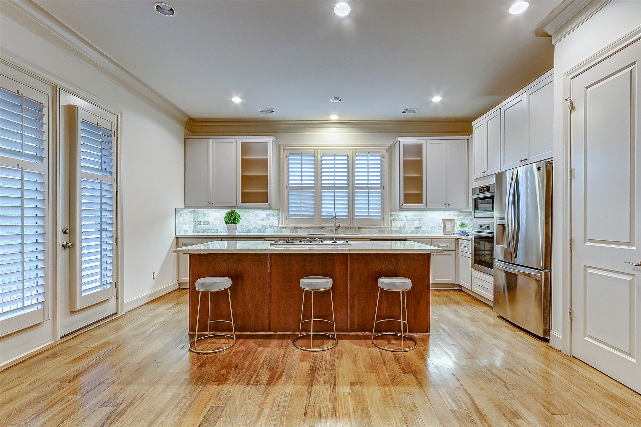 Spacious kitchen with sleek stainless steel appliances, a central island with seating, and elegant cabinetry, all illuminated by soft recessed lighting.