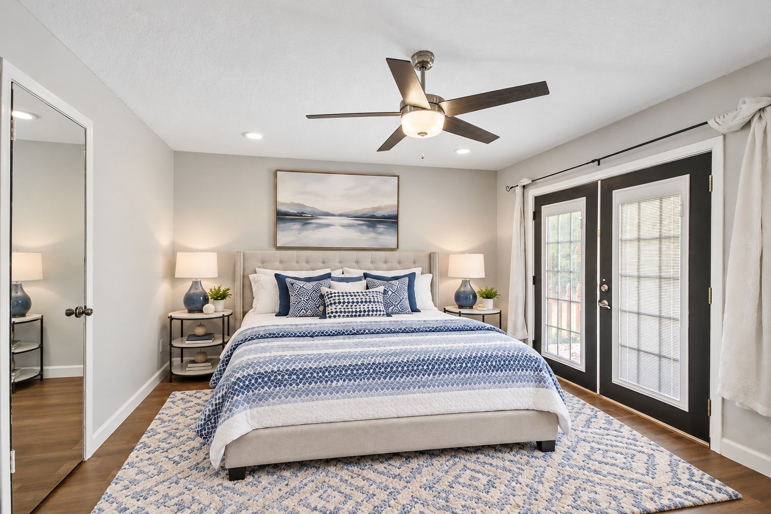The primary bedroom offers a spacious retreat with dark wood-look flooring, a ceiling fan, and French doors that bring in plenty of natural light. Virtually staged. The primary bedroom offers a spacious retreat with dark wood-look flooring, a ceiling fan, and French doors that bring in plenty of natural light. Virtually staged.
