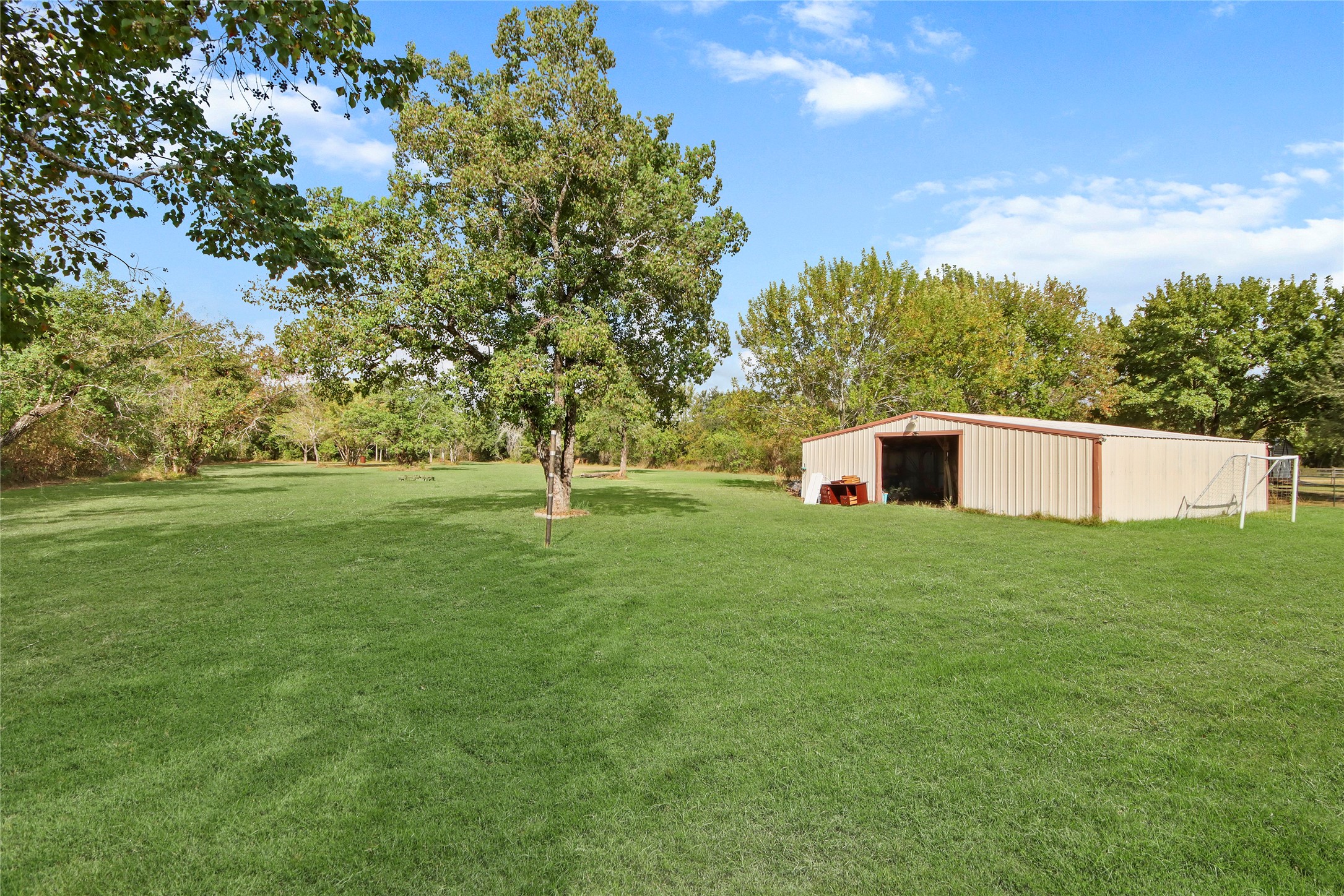 Tucked at the edge of the expansive lot, a large storage shed offers abundant space for equipment, tools, lawn gear, or a future workshop.