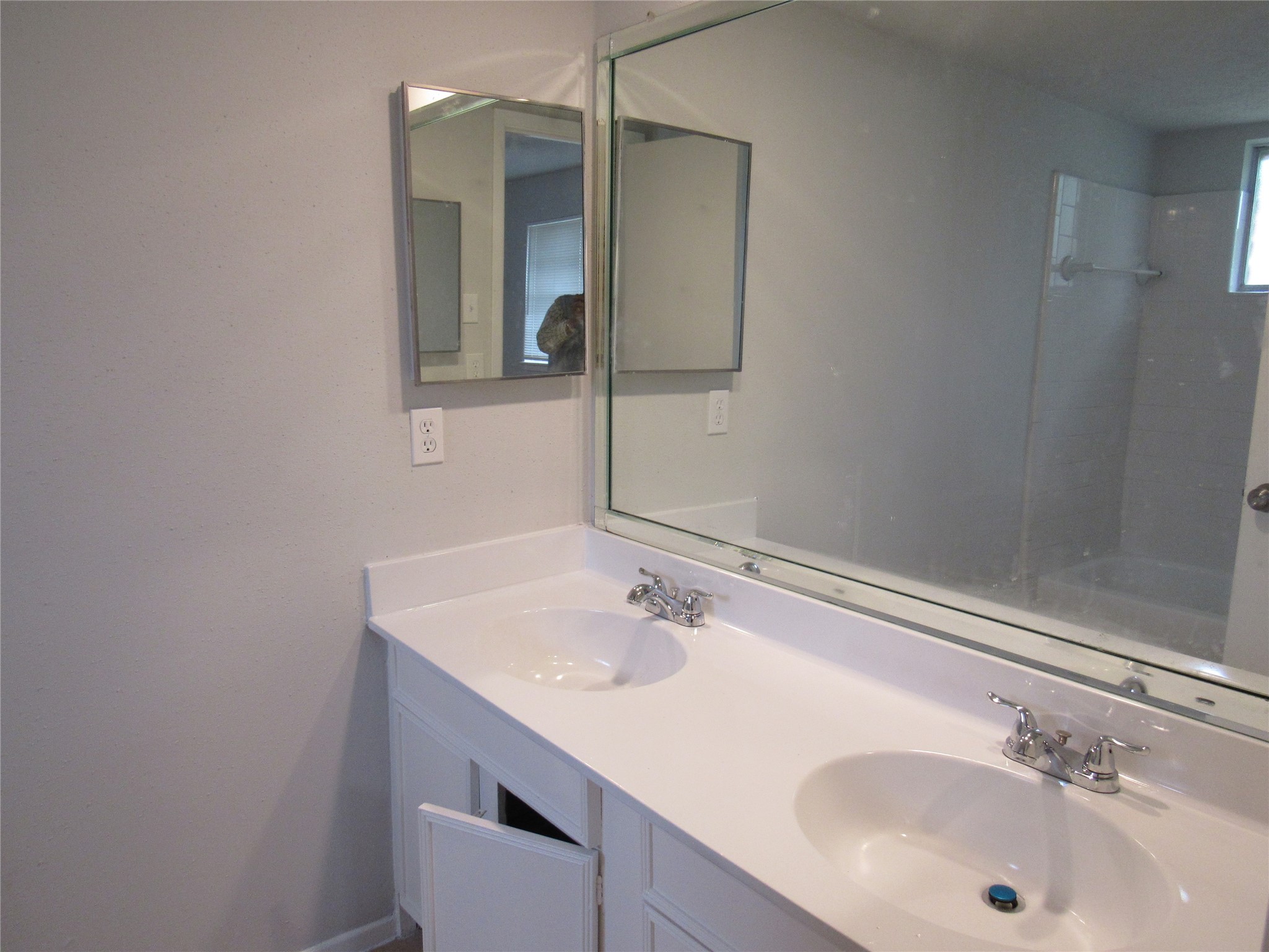 View of the master bathroom with double sinks, man-made counter, commode, medicine counter, and tub.