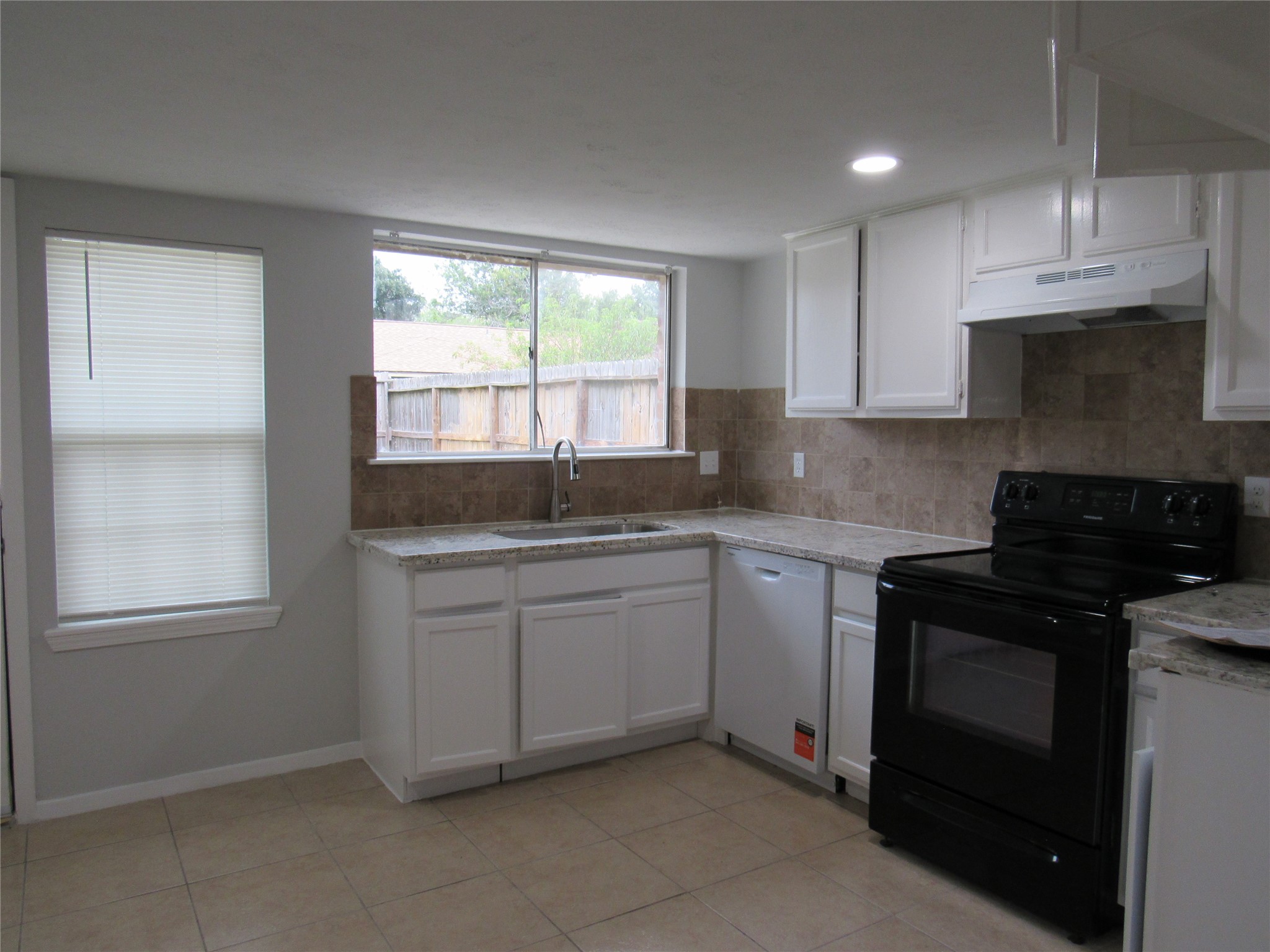 Large clean kitchen with granite counters, door to back yard and space for breakfast table.