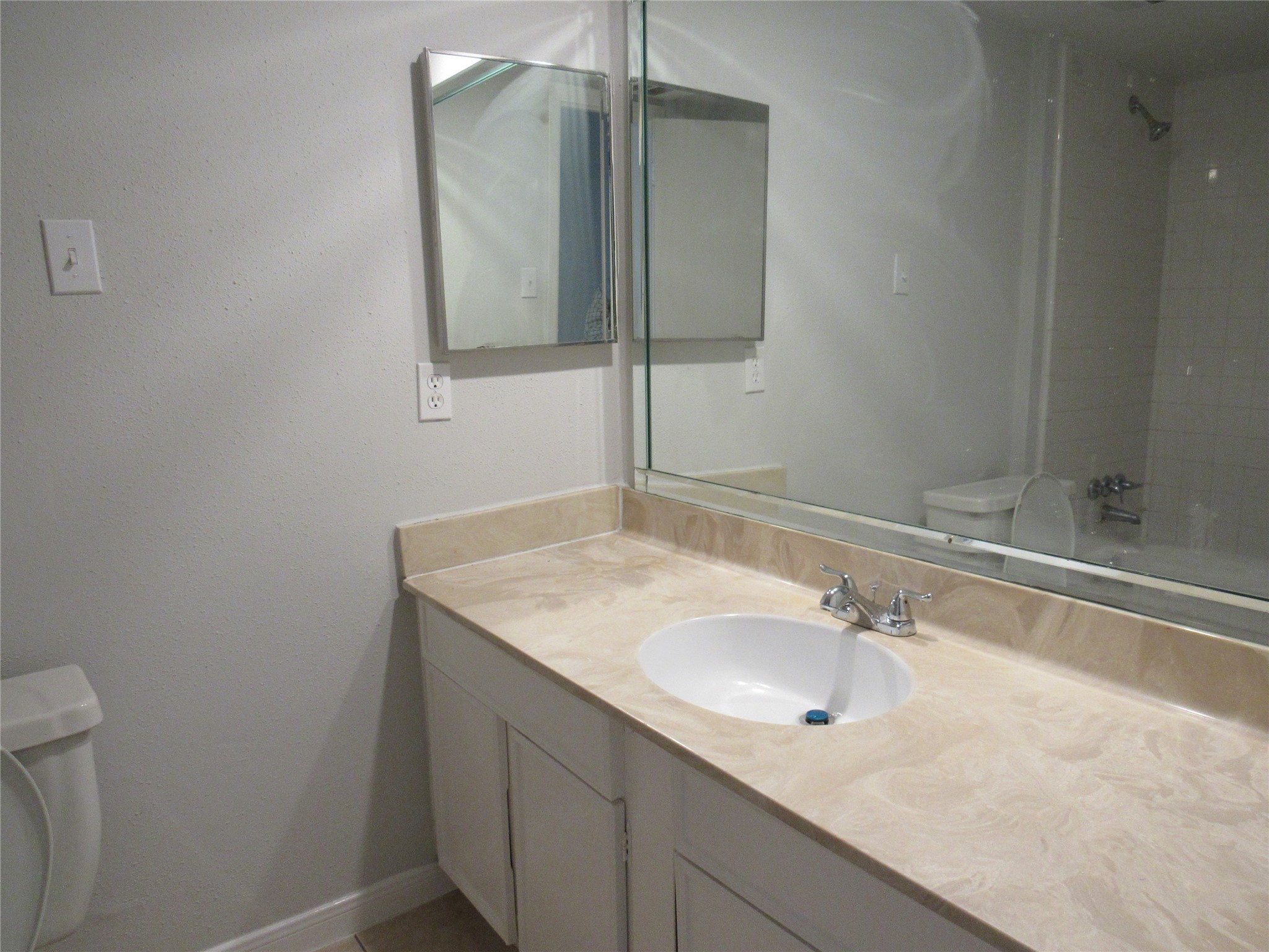 Hall bathroomwith medicine cabinet, single sink, man-made marble counter, cammode, & tub