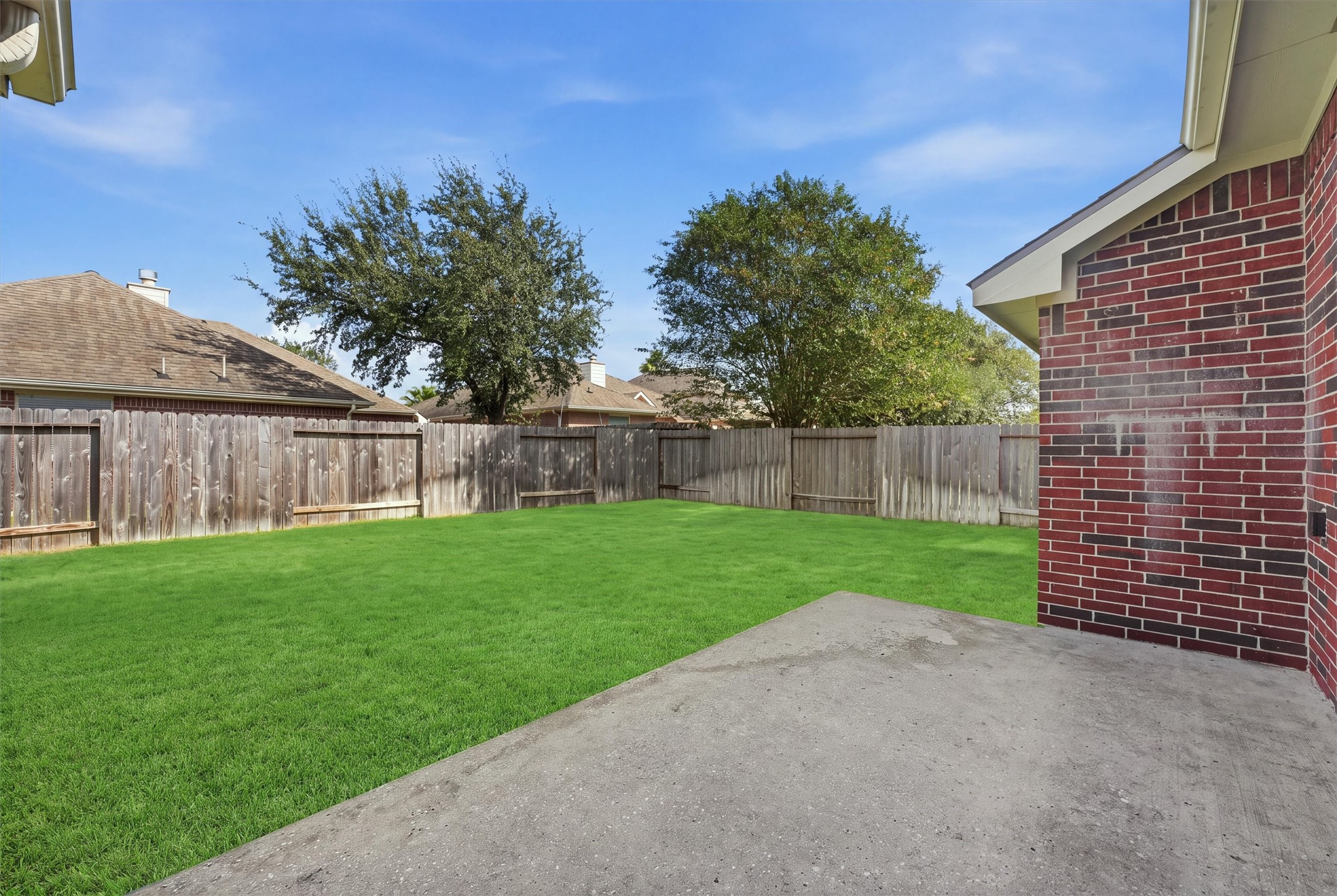Spacious backyard with lush green lawn and a sturdy wooden fence, perfect for outdoor activities and privacy.