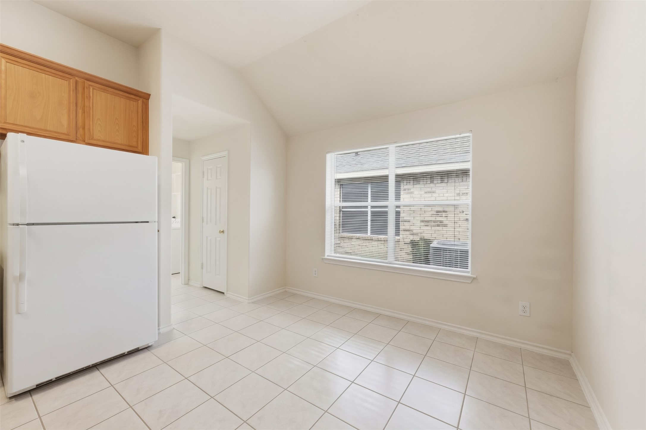 Bright kitchen area with large window, tiled flooring, and ample cabinet space.