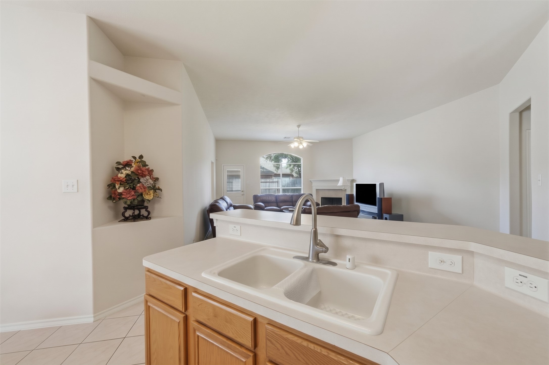 Spacious open-concept living area with a view from the kitchen sink, featuring a cozy living room, neutral tones, and abundant natural light.