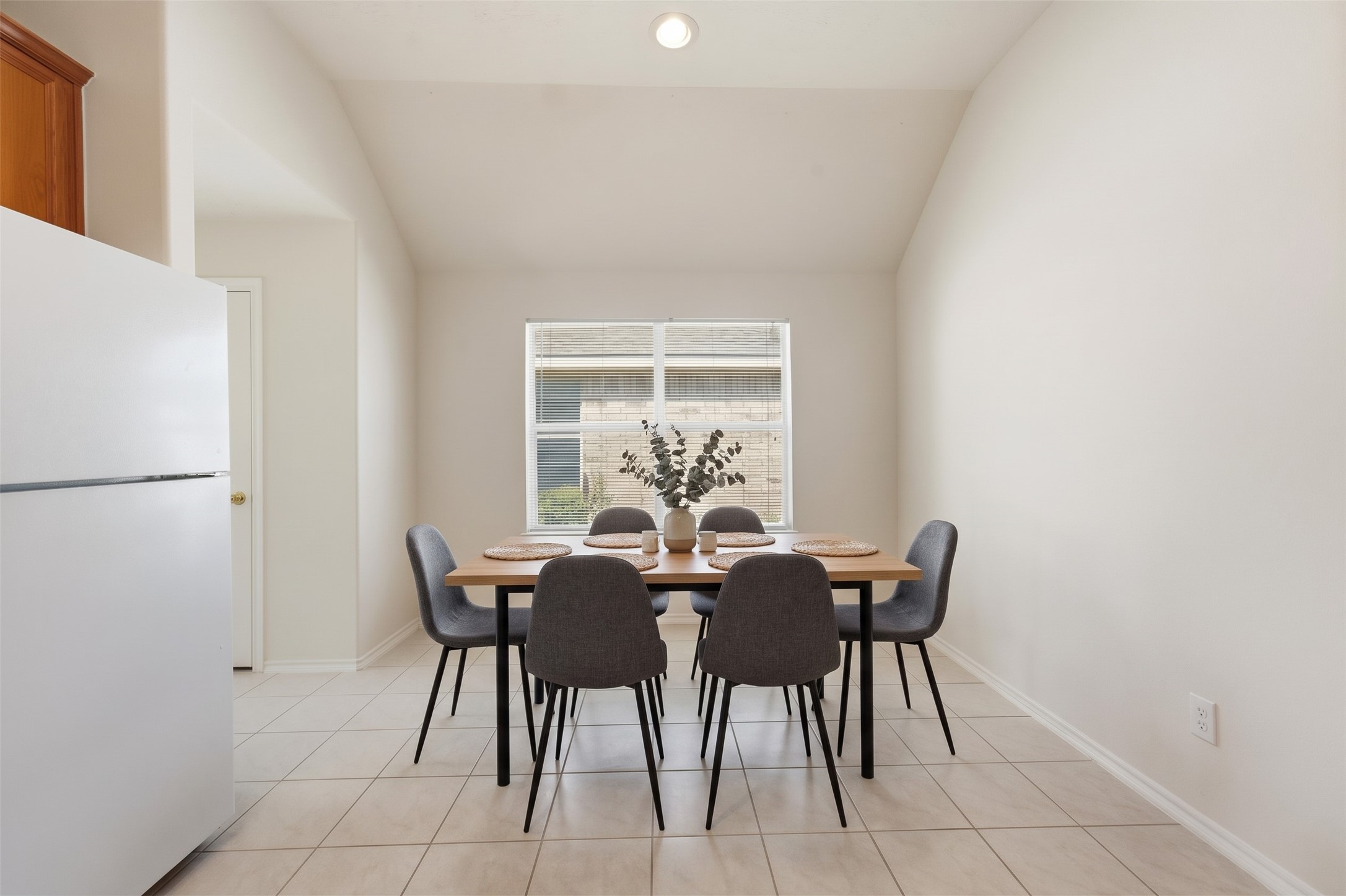 Bright kitchen area with large window, tiled flooring, and ample cabinet space.