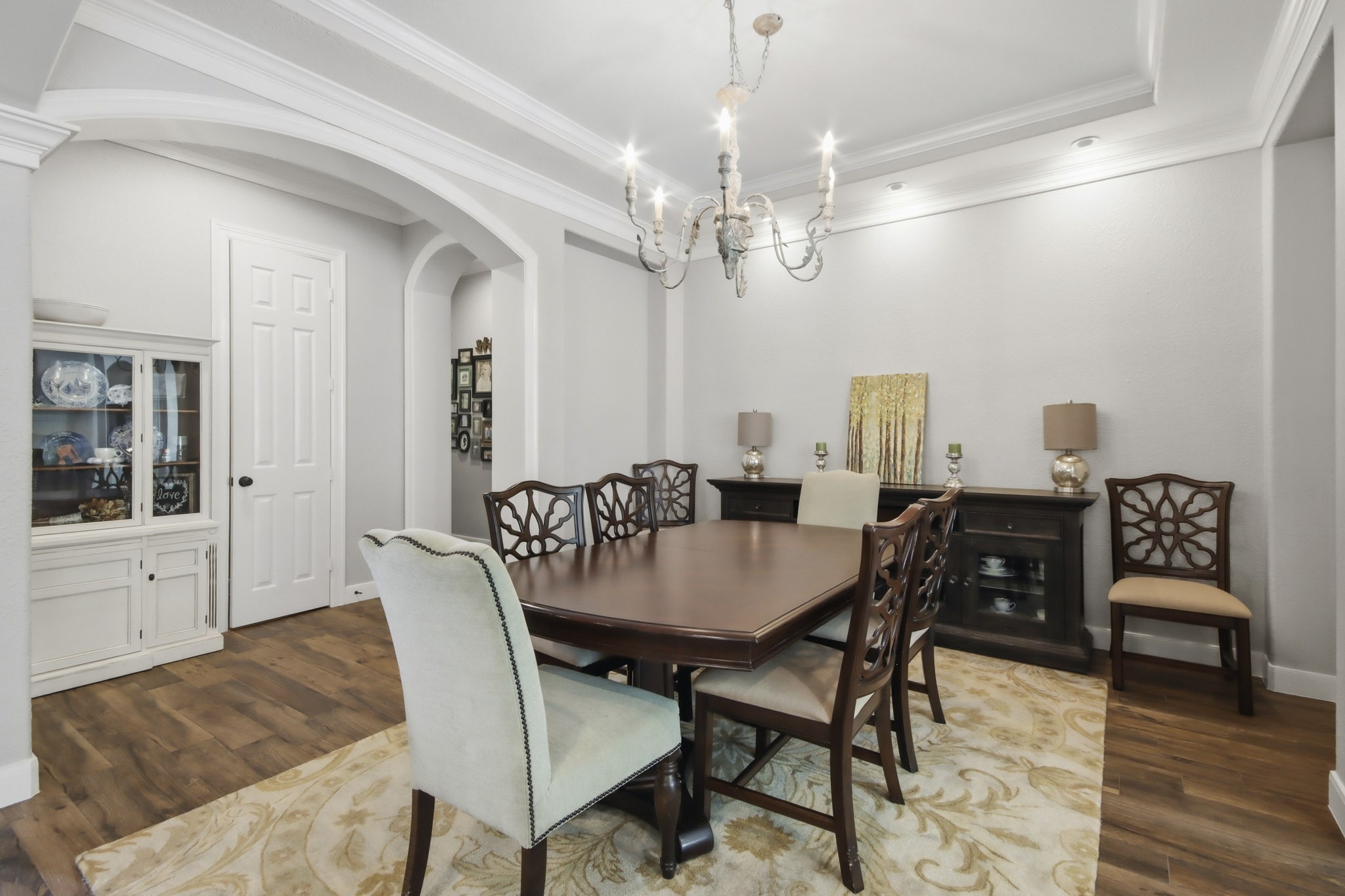 Dining room featuring an intricate chandelier, tray ceiling, and arched entry ways.