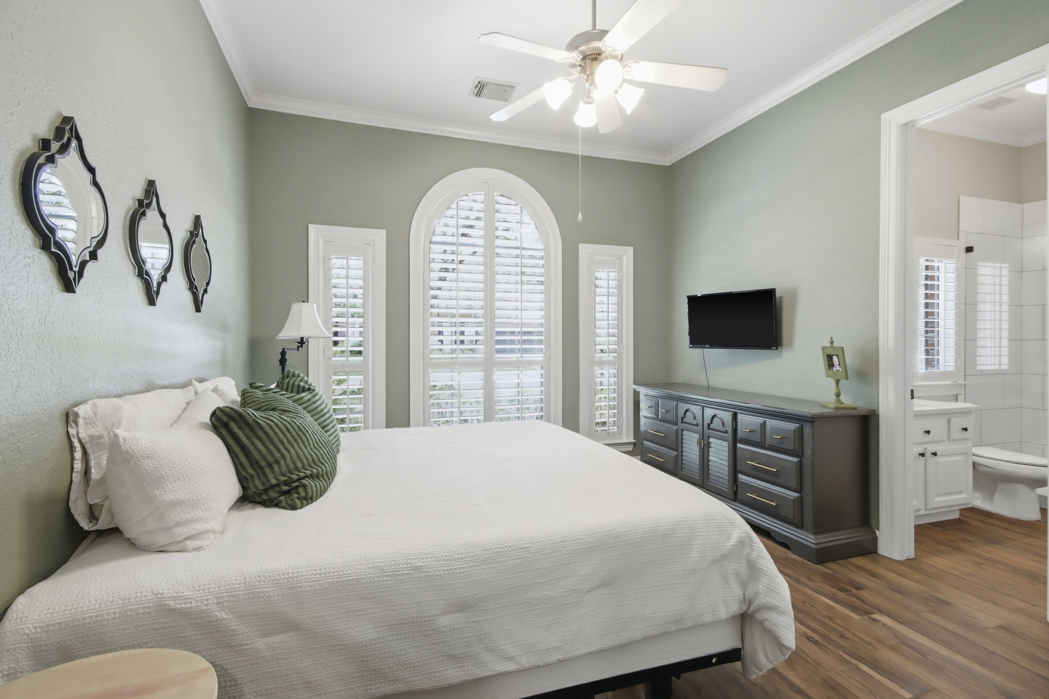 Downstairs secondary bedroom with elegant arched window, abundant natural light, and an en-suite bathroom for added convenience.