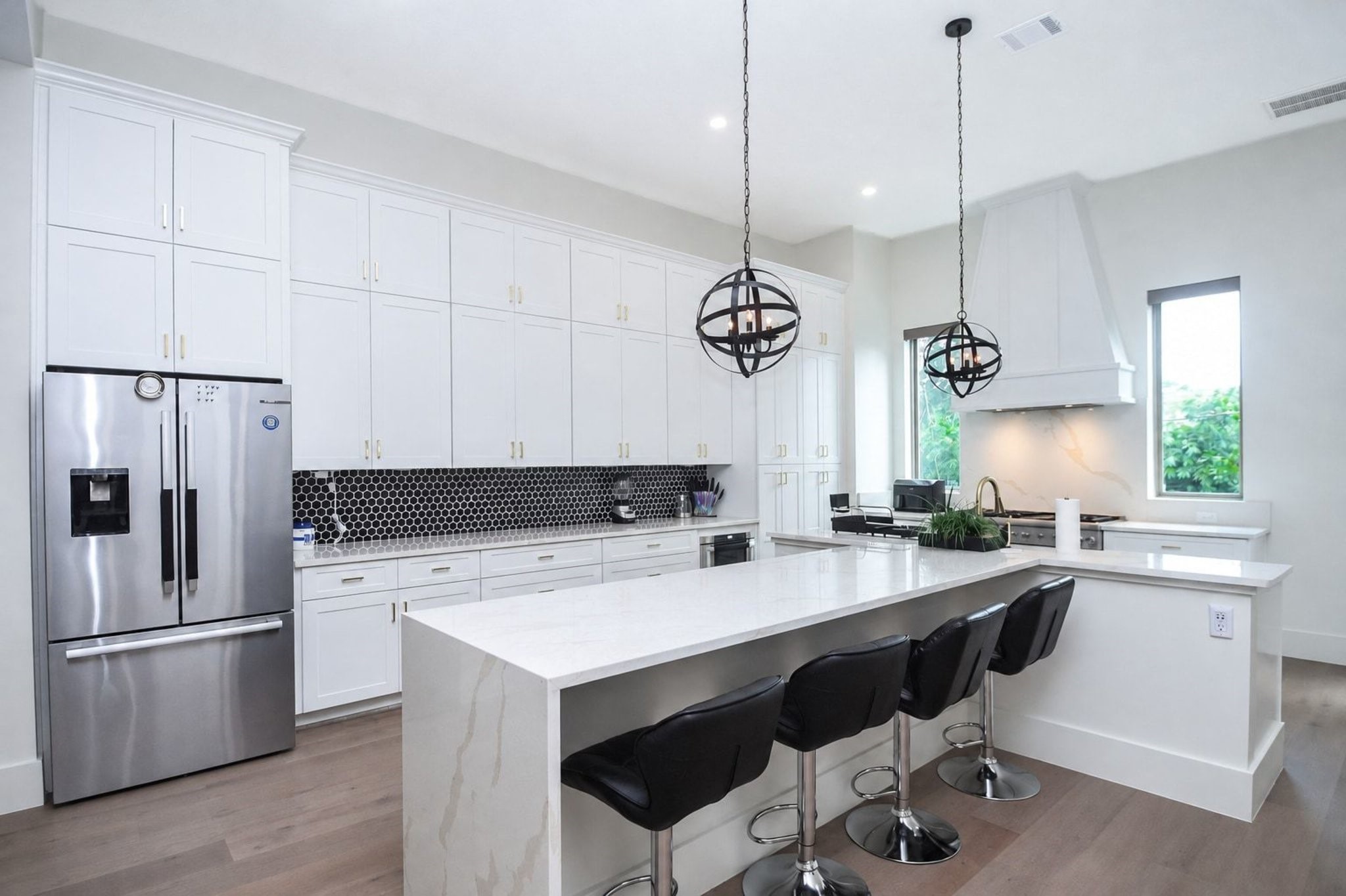 Comfortable counter seating is perfect for quick snacks or everyday meals in the recessed space under the generous island. Don't you love the globe shaped metal fixtures above --- and brilliant natural light filtering through the good looking windows on either side of the sink? Top of the line Thermador and Bosch appliances grace this kitchen.