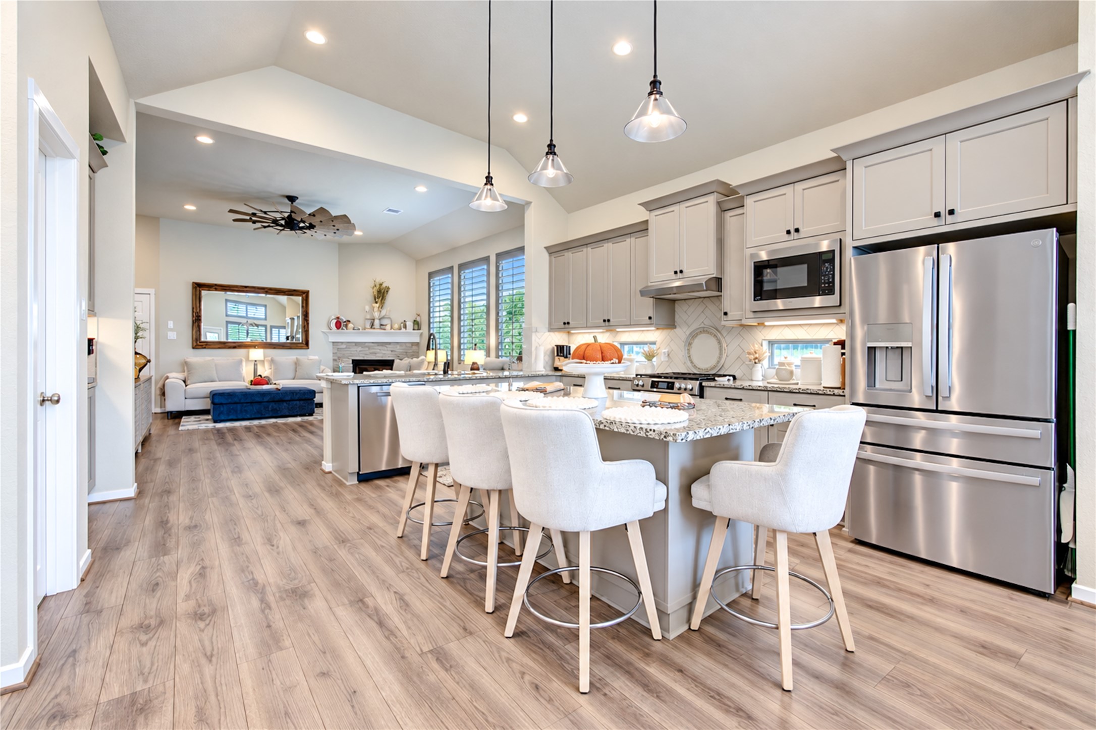 The open kitchen features generous counter space, a large island, shaker-style cabinetry and stainless steel appliances, all overlooking the family room.