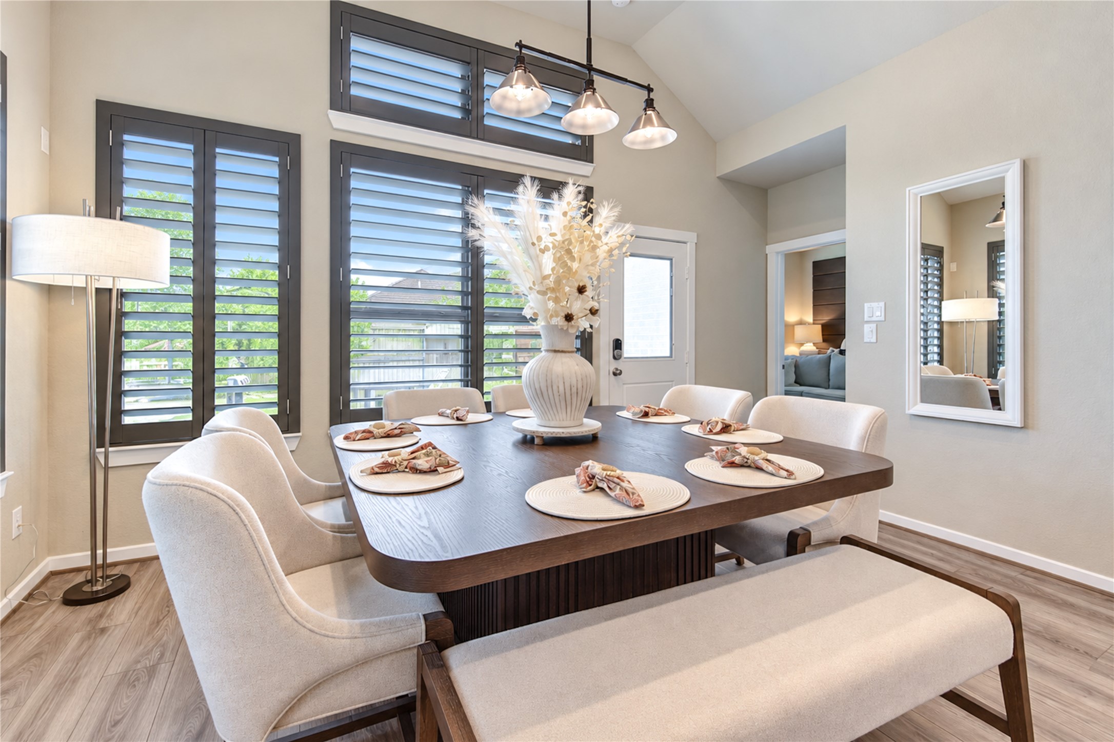 Natural light fills the dining area, with tall windows, plantation shutters and attractive pendant lighting.