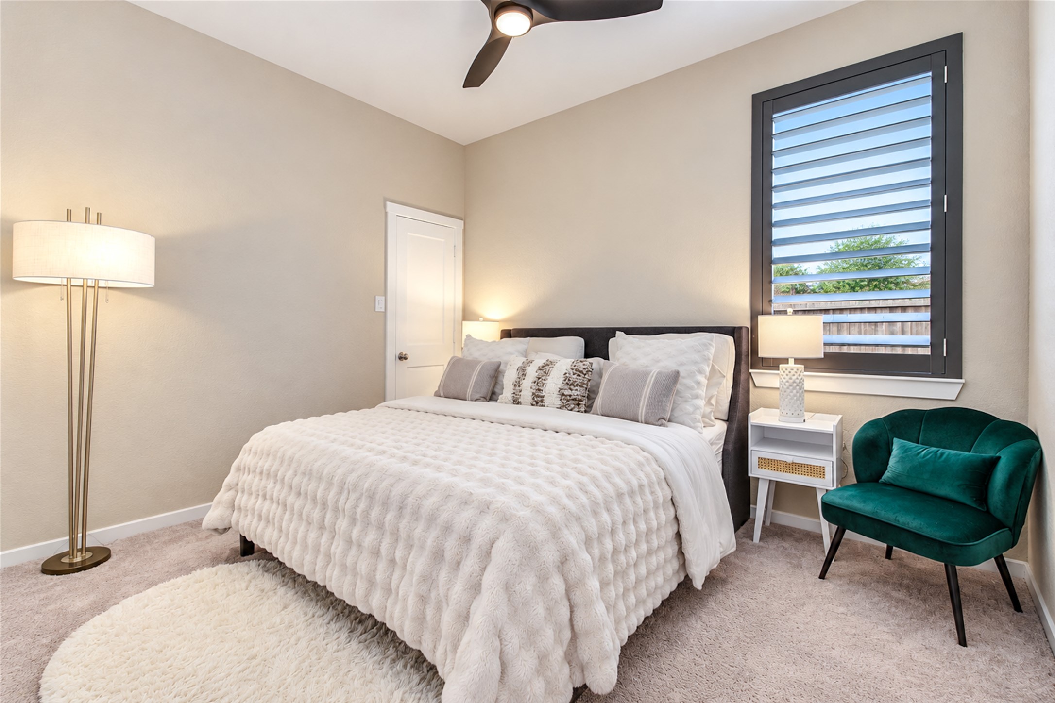 Another inviting bedroom with natural light, plantation shutters and a ceiling fan.