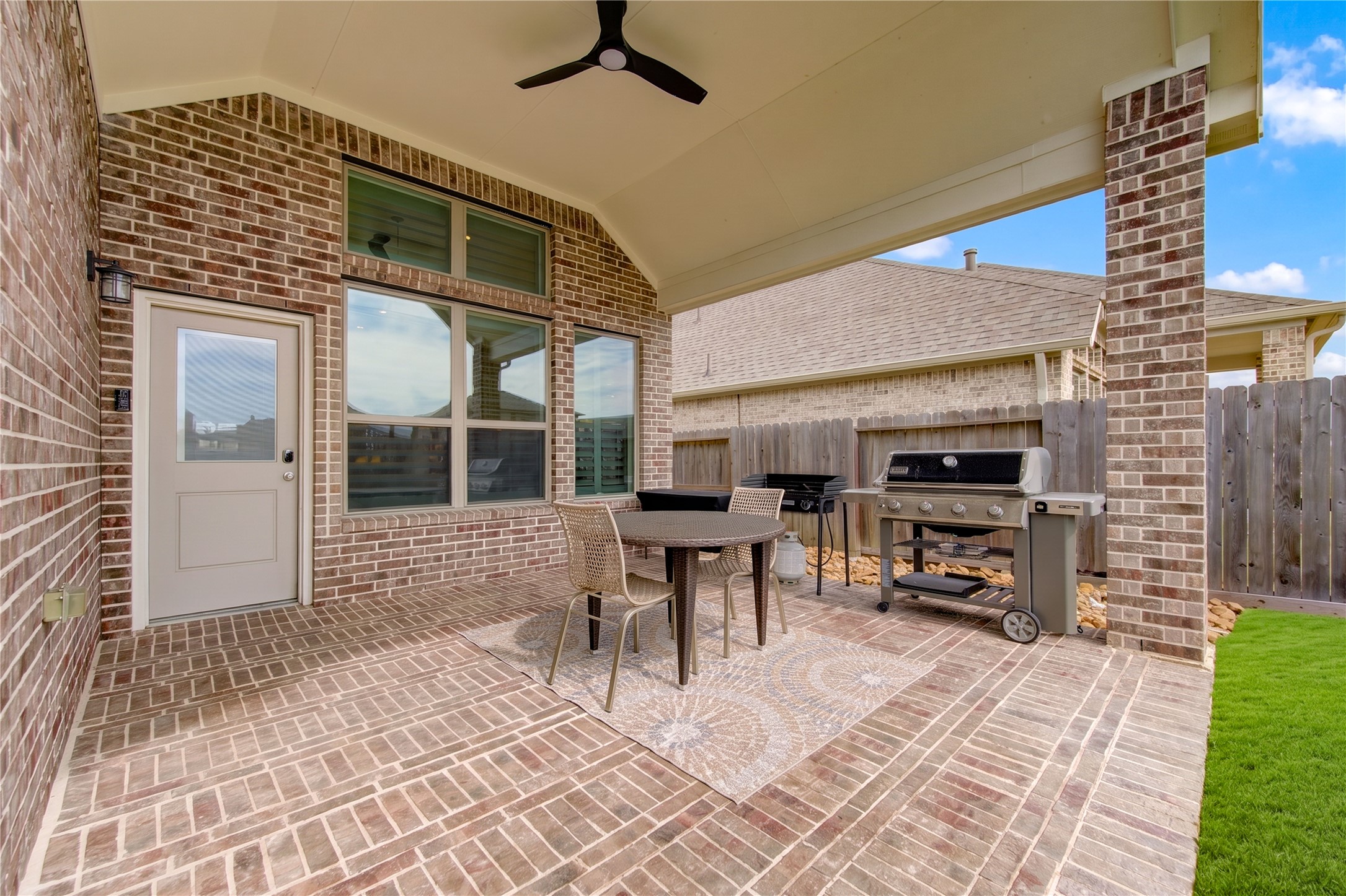 A generous covered patio with brick flooring, a ceiling fan and plenty of room for outdoor entertaining.