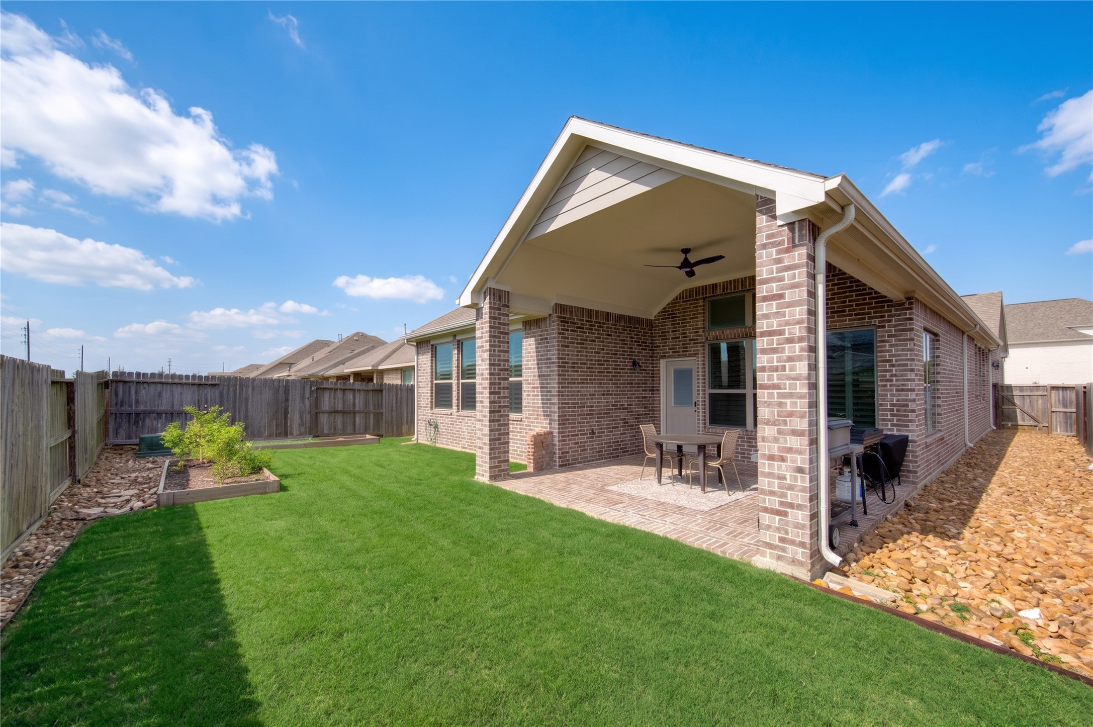 The backyard features a covered patio, green space and a nicely maintained rear exterior.