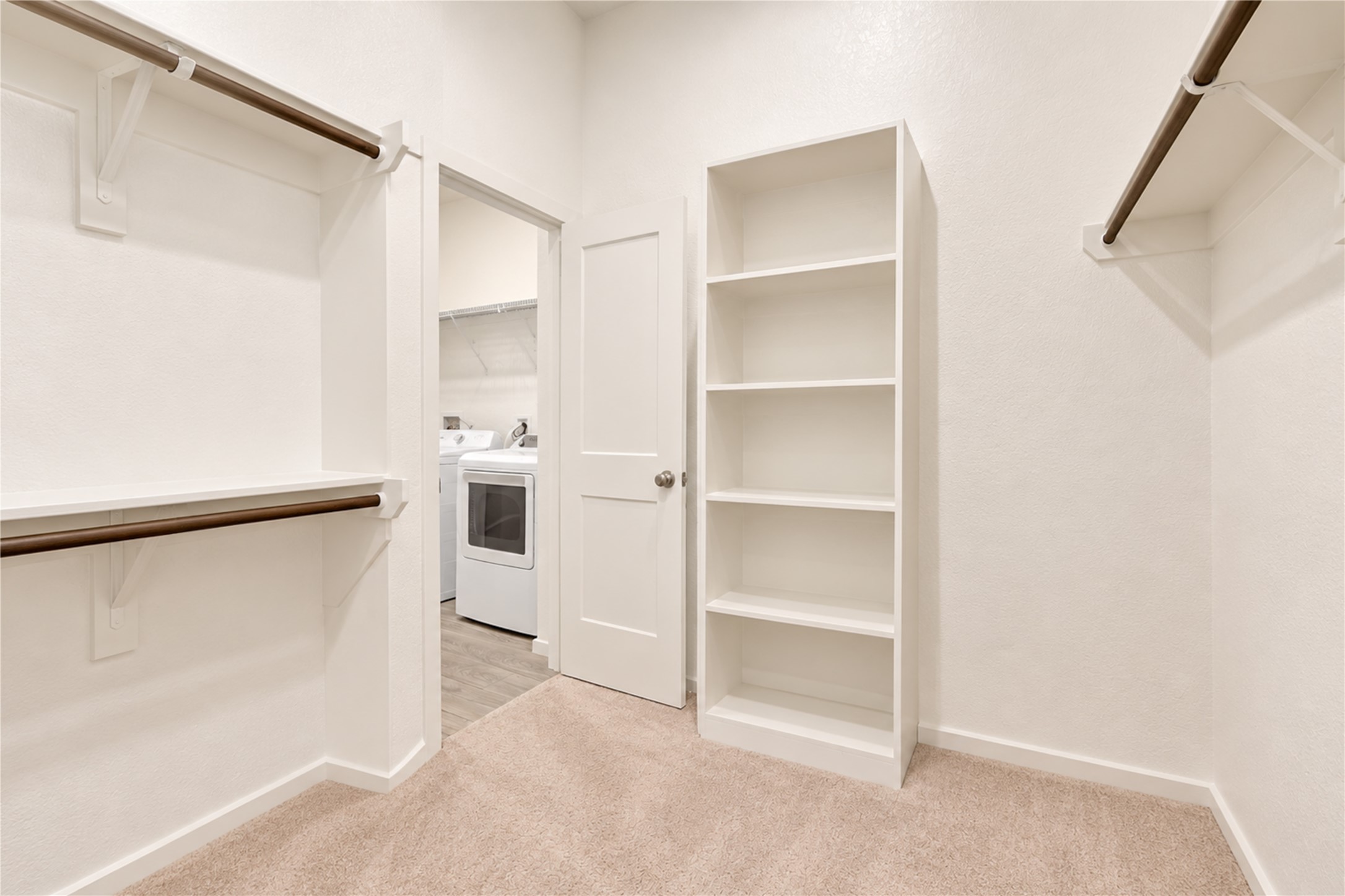 A generous walk-in closet with built-in shelving and hanging space, plus convenient direct access to the utility room.