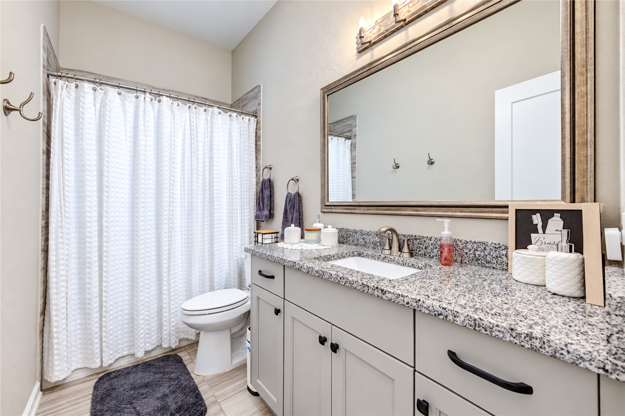 The secondary bathroom features a spacious vanity with granite countertops, generous cabinet storage and a tub/shower combination.