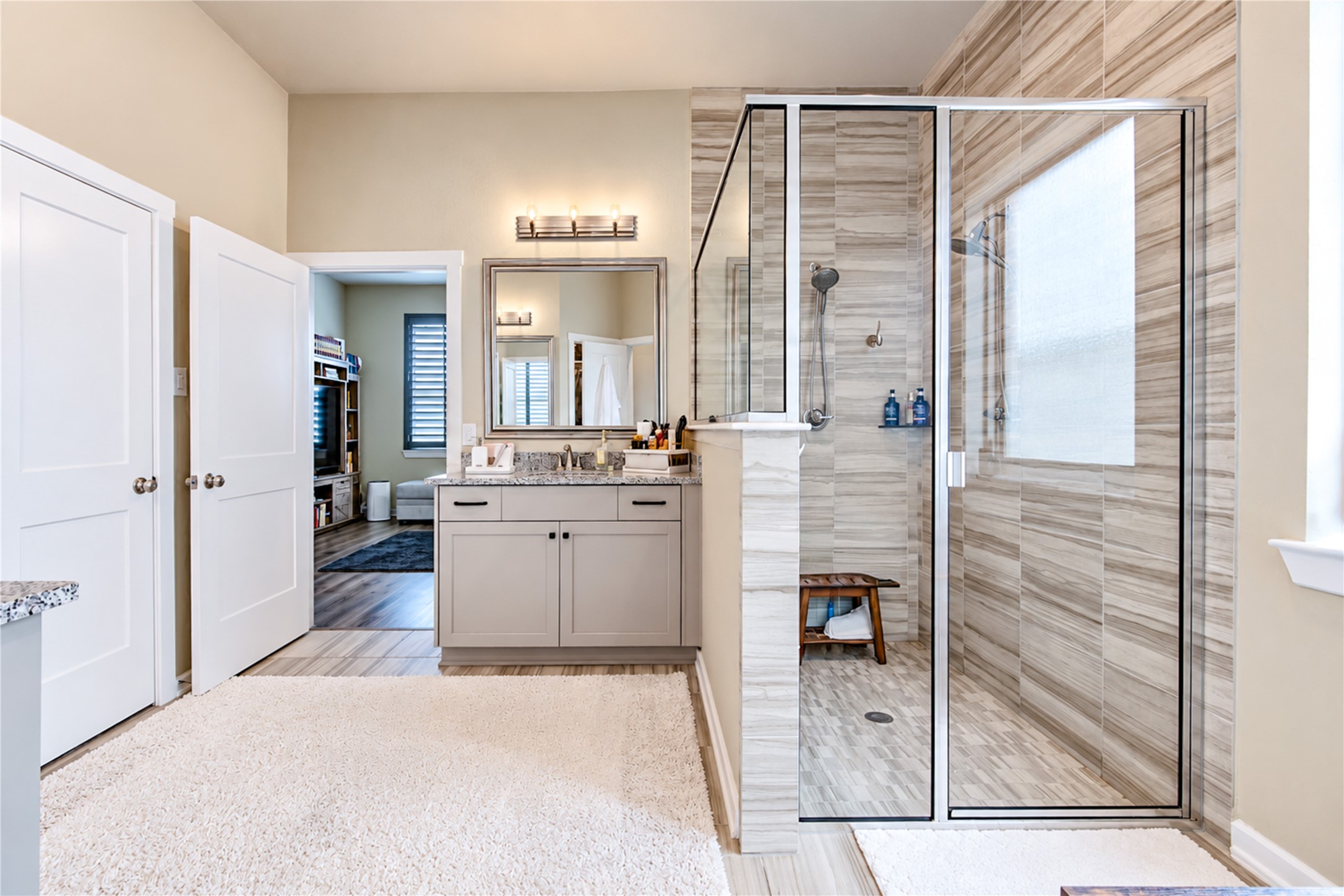 A closer look at the primary bath's large, glass-enclosed shower with floor-to-ceiling tile and dual showerheads.