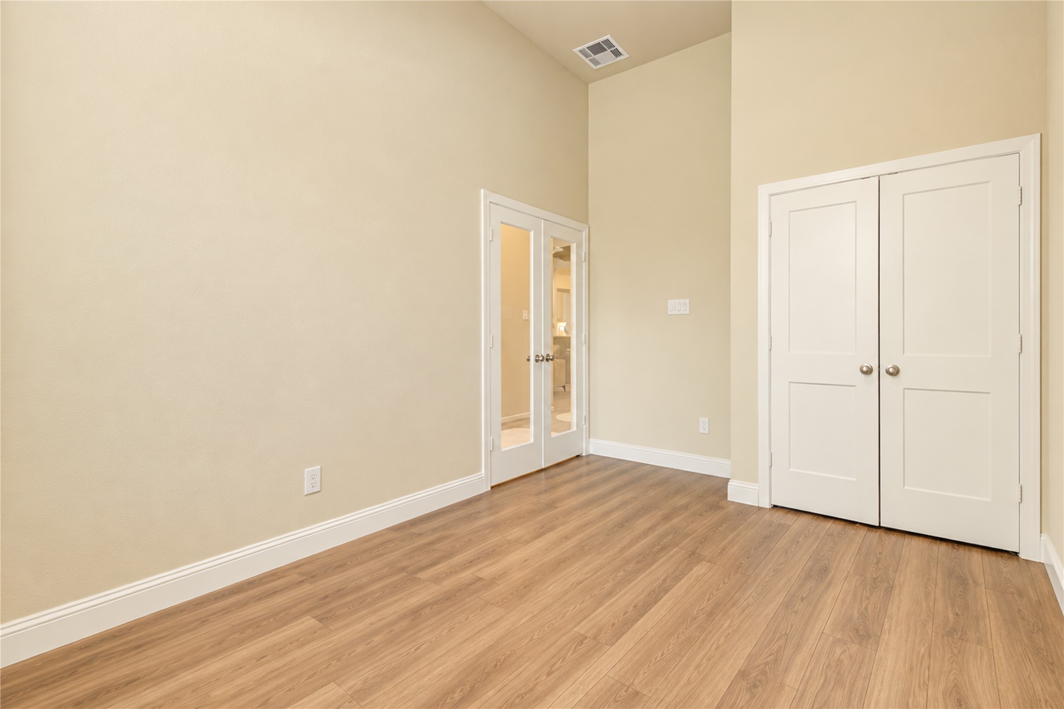 Another view of the flexible space, featuring double French doors and a convenient closet.