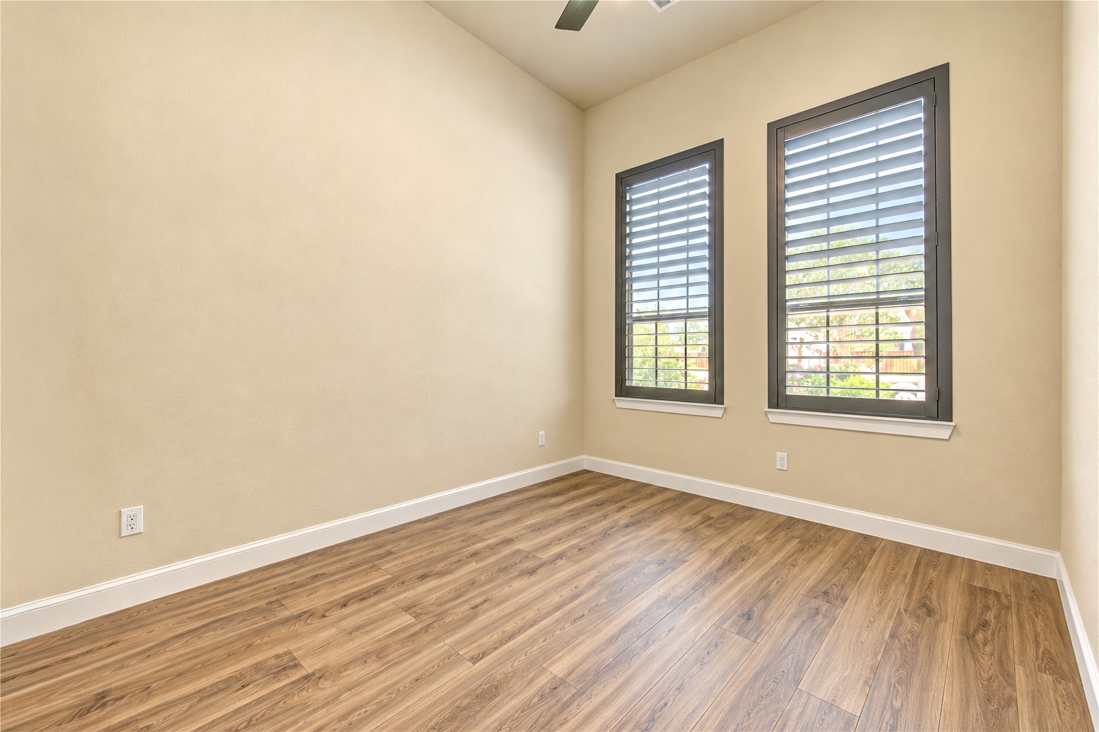 A versatile room with high ceilings, plantation shutters and wood-look tile flooring. Ideal for a home office or additional bedroom space.