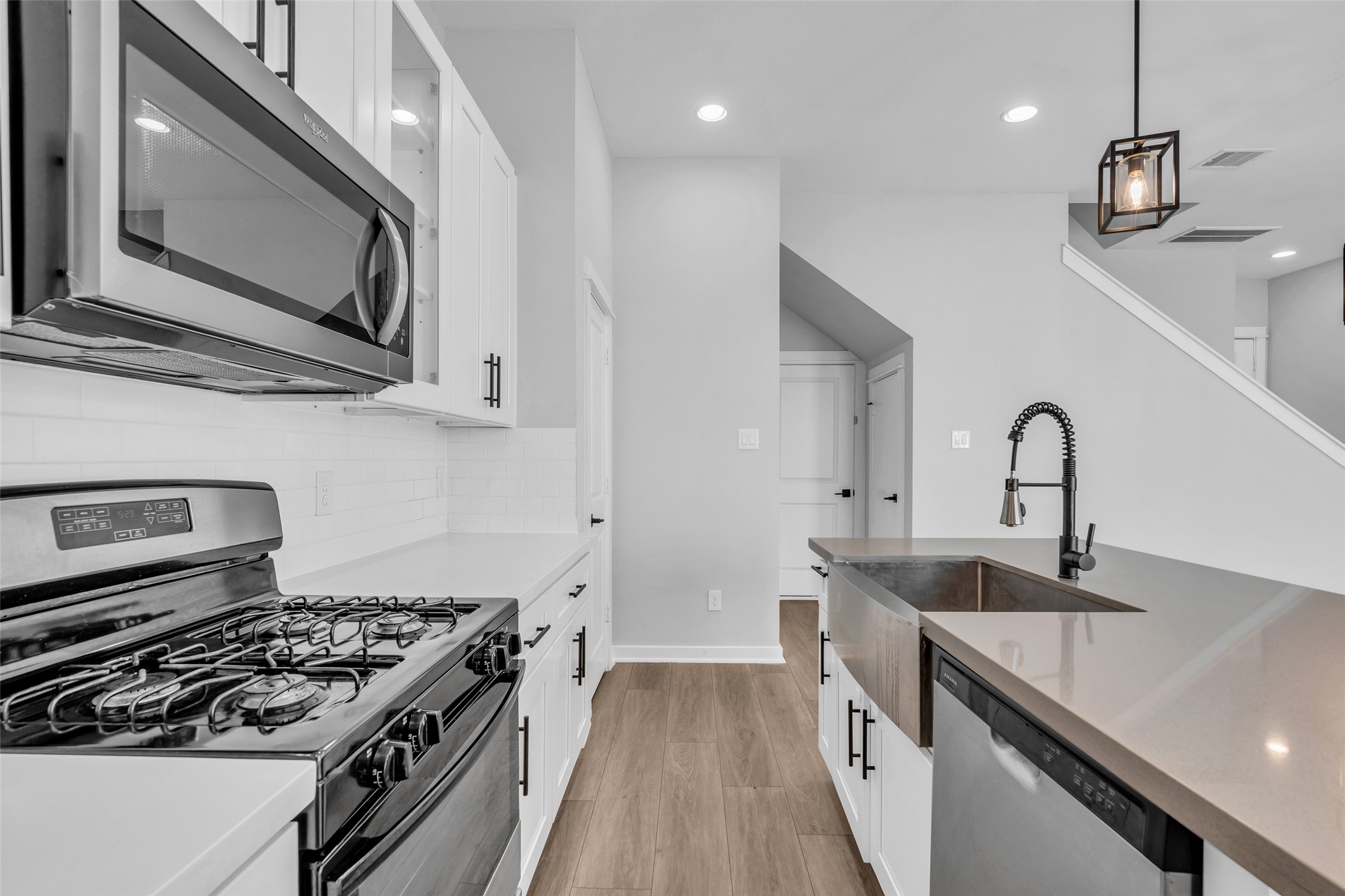 Cook on a gas range with an over-the-range microwave and cabinetry close at hand.