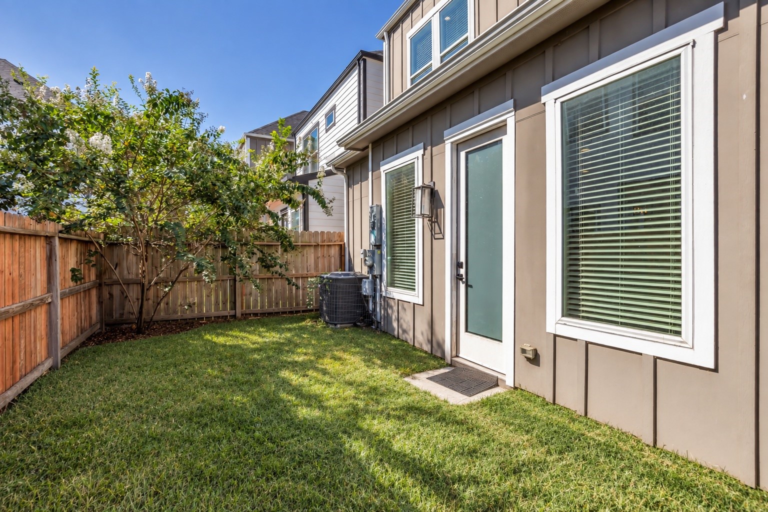 A private, fenced backyard shaded by a mature tree.