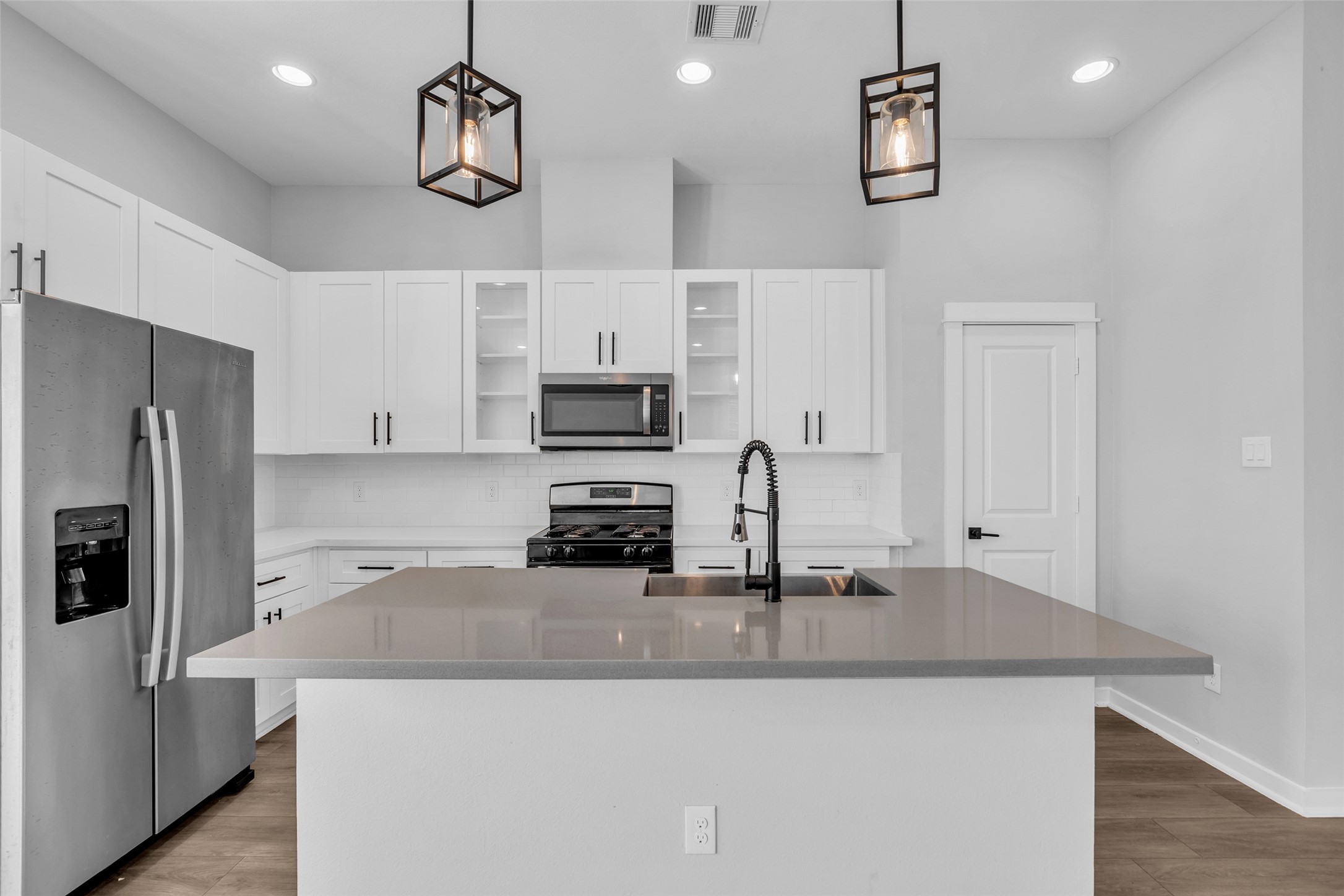 A cook's kitchen with a large center island, stainless steel appliances and plenty of white shaker cabinetry. A cook's kitchen with a large center island, stainless steel appliances and plenty of white shaker cabinetry.