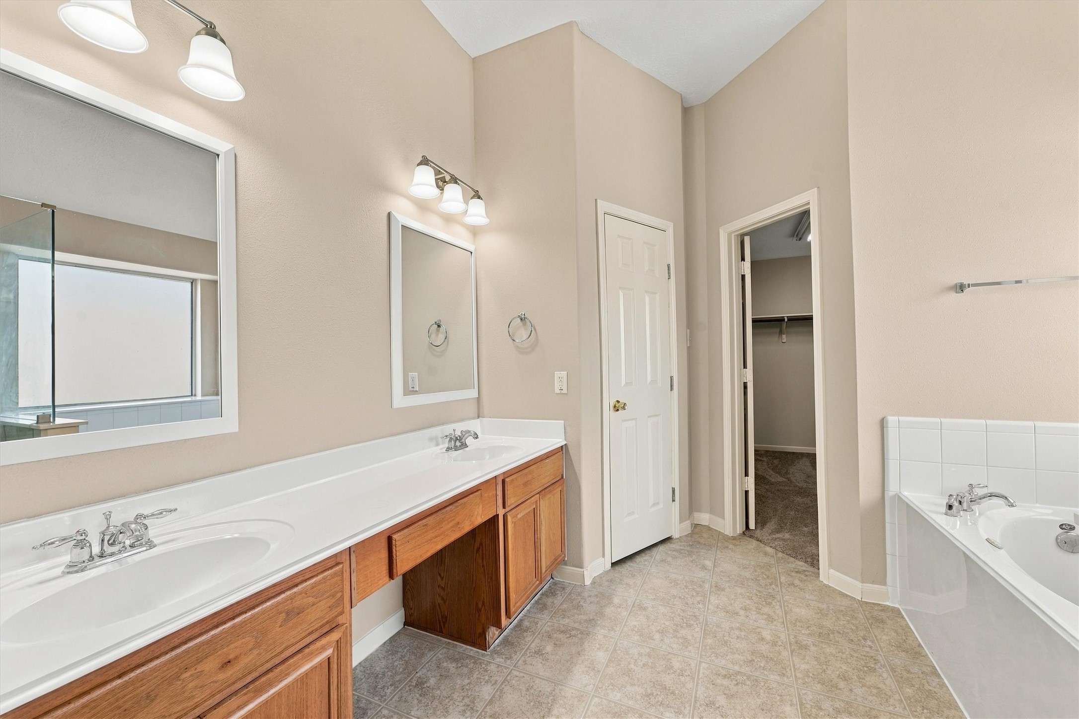 Experience luxury in the primary bathroom featuring dual sinks, elegant fixtures, and a spacious layout perfect for relaxation and convenience.