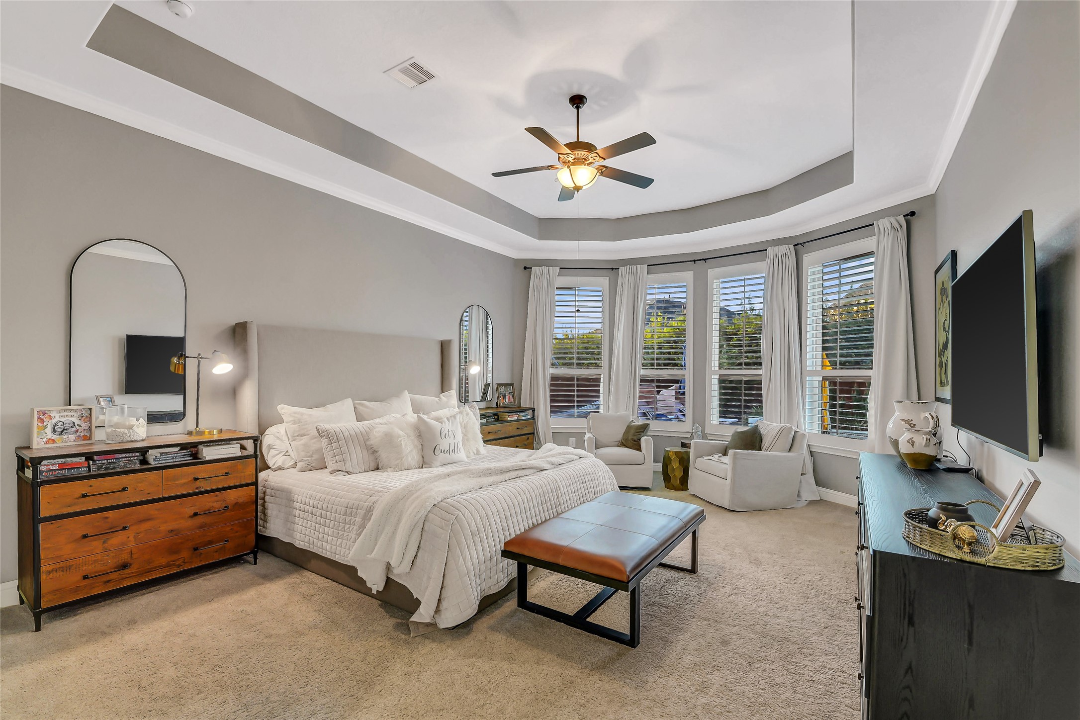 Retreat to the spacious primary suite, featuring an elegant tray ceiling, a cozy sitting area, and a wall of windows that fills the room with natural light. This serene sanctuary offers the perfect blend of comfort and sophistication, creating a peaceful escape at the end of the day.