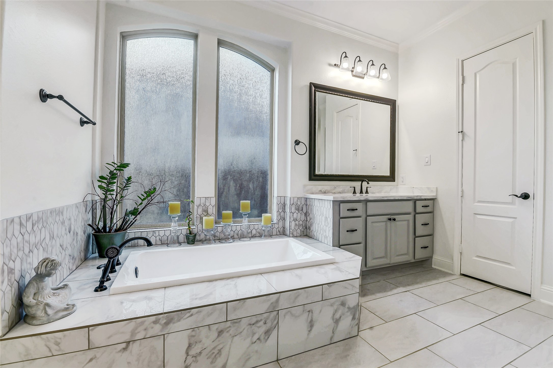 Luxurious soaking tub creates the perfect retreat with elegant tile surround and oversized arched windows.