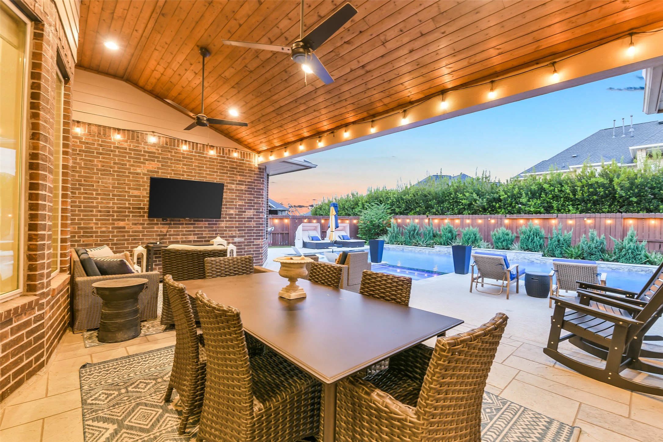Step outside to outdoor living at its finest with this stunning covered patio featuring a beautiful tongue-and-groove wood ceiling, dual ceiling fans, and recessed lighting. Overlooking the sparkling pool and surrounded by lush landscaping, this thoughtfully designed space is perfect for dining, entertaining, and relaxing year-round.