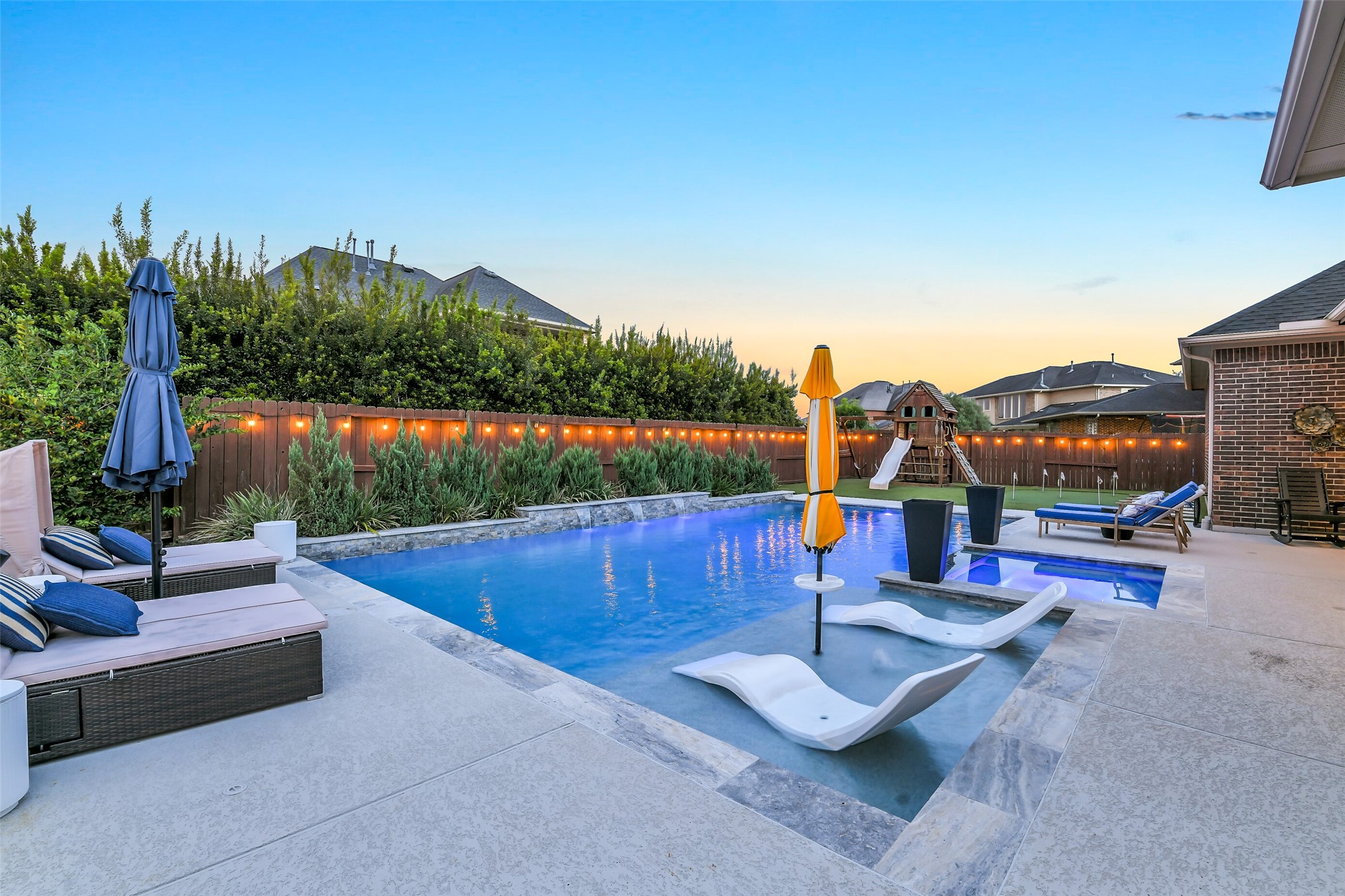 Relax in your private backyard oasis featuring a tanning ledge, a tranquil cascading waterfall, and a heated pool/spa. Surrounded by well-manicured landscaping and lush turf, ample decking provides plenty of space for lounging, entertaining, and enjoying the outdoor lifestyle.