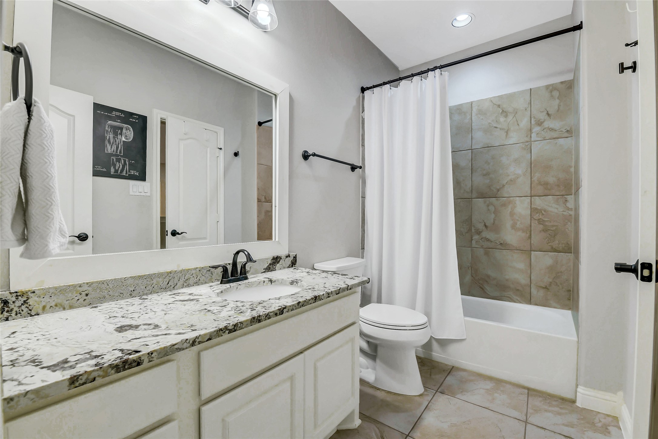 This upstairs full bathroom offers convenient access from both the adjacent bedroom and the hallway, featuring a granite vanity, tiled tub/shower combination and quality finishes that comfortably serve family members and guests.