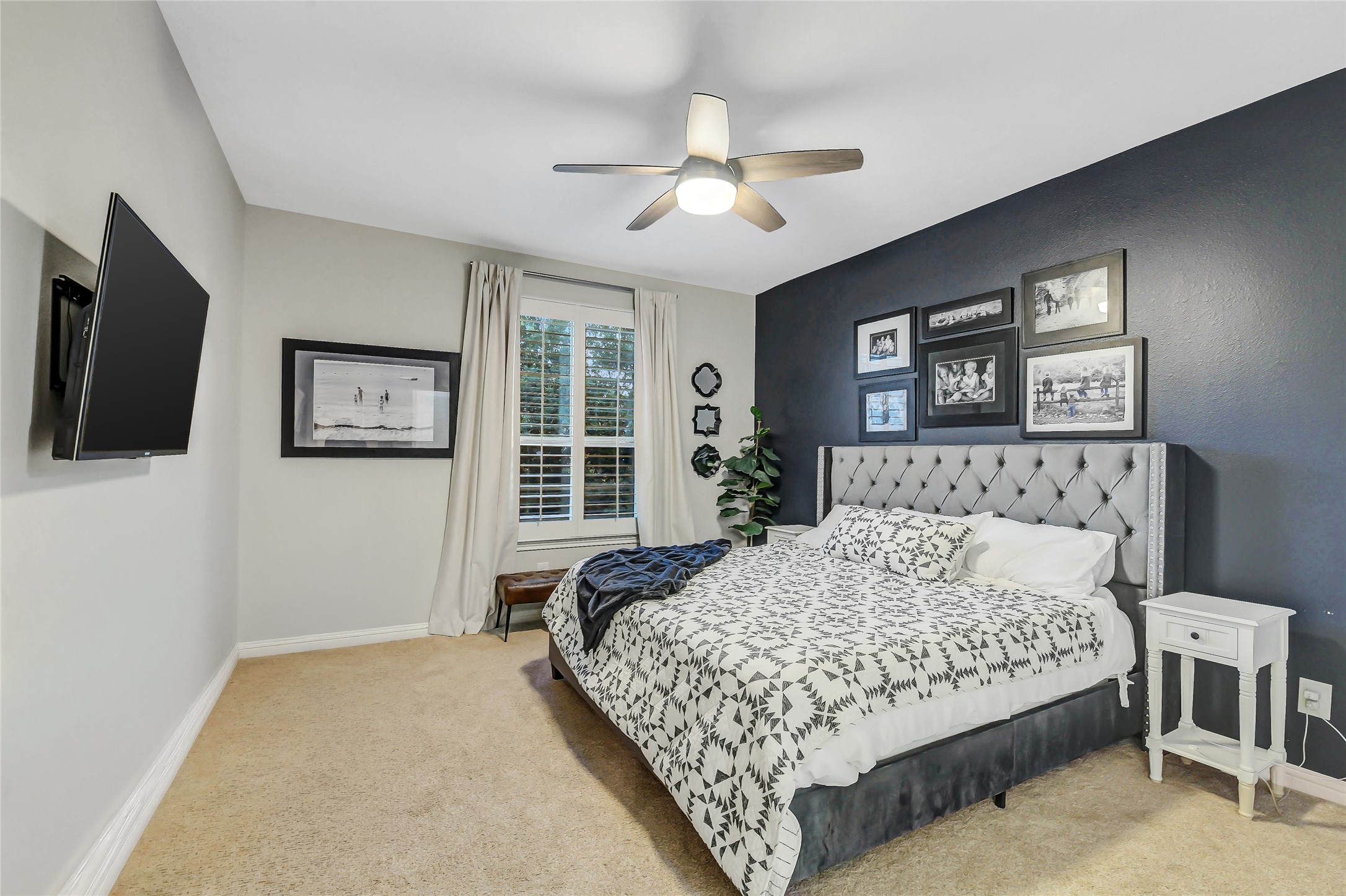 Front-facing secondary bedroom featuring plantation shutters, a ceiling fan and a spacious walk-in closet.