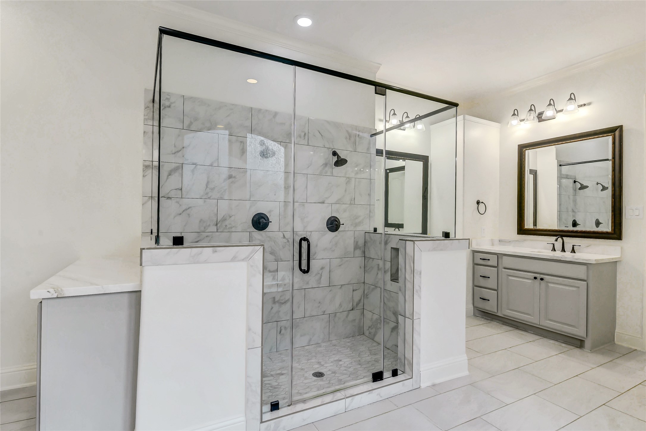 Elegant primary bathroom featuring a large walk-in shower with dual showerheads, two separate sink areas along with a separate vanity area and private water closet.