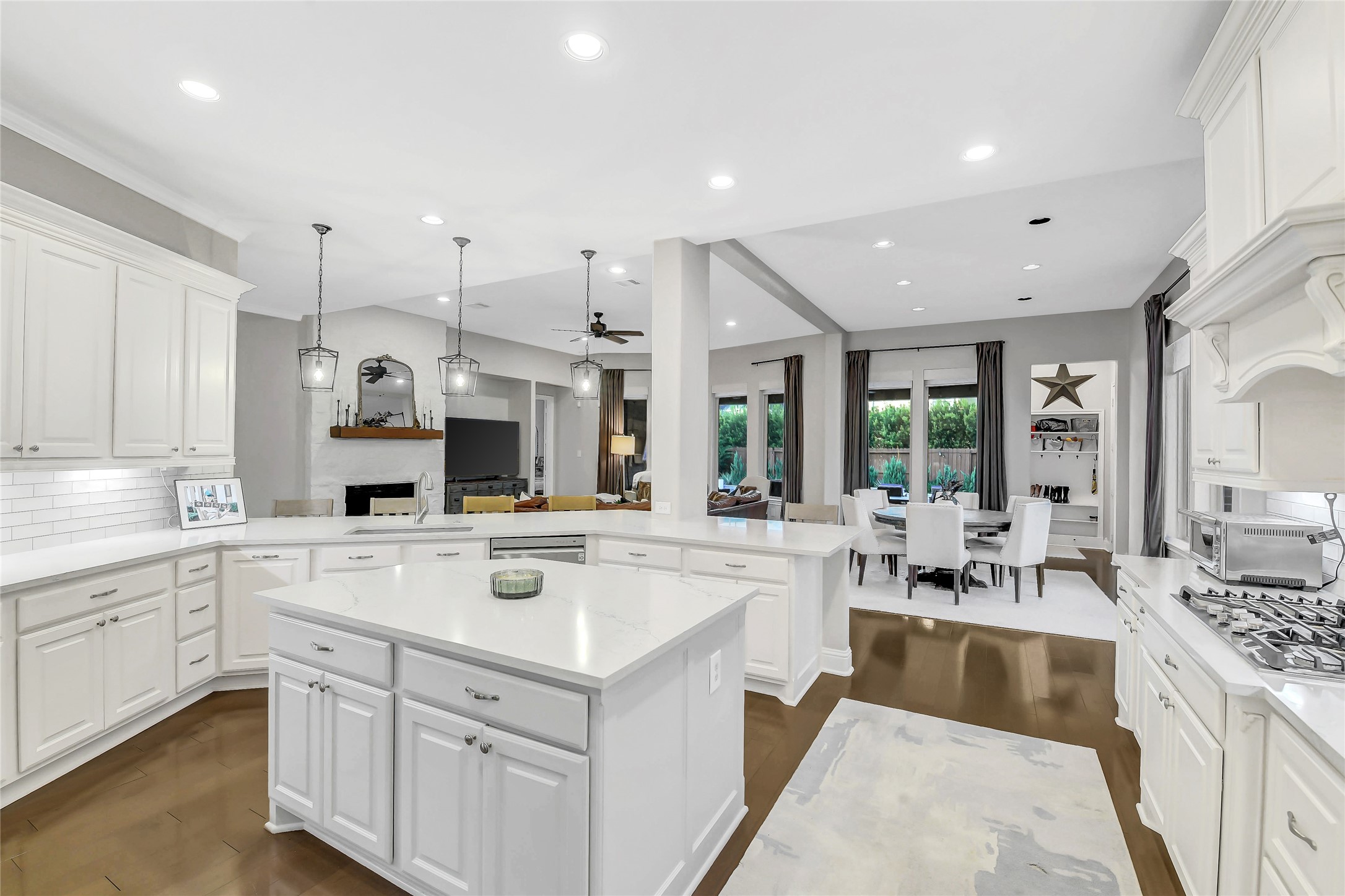 The chef-inspired kitchen showcases crisp white cabinetry, sleek countertops, built-in stainless steel GE cafe appliances, a large breakfast bar and a center island that serves as the heart of the home. Thoughtfully designed with extensive workspace, under-cabinet lighting, and an airy layout, it blends style and functionality for effortless cooking and gathering.