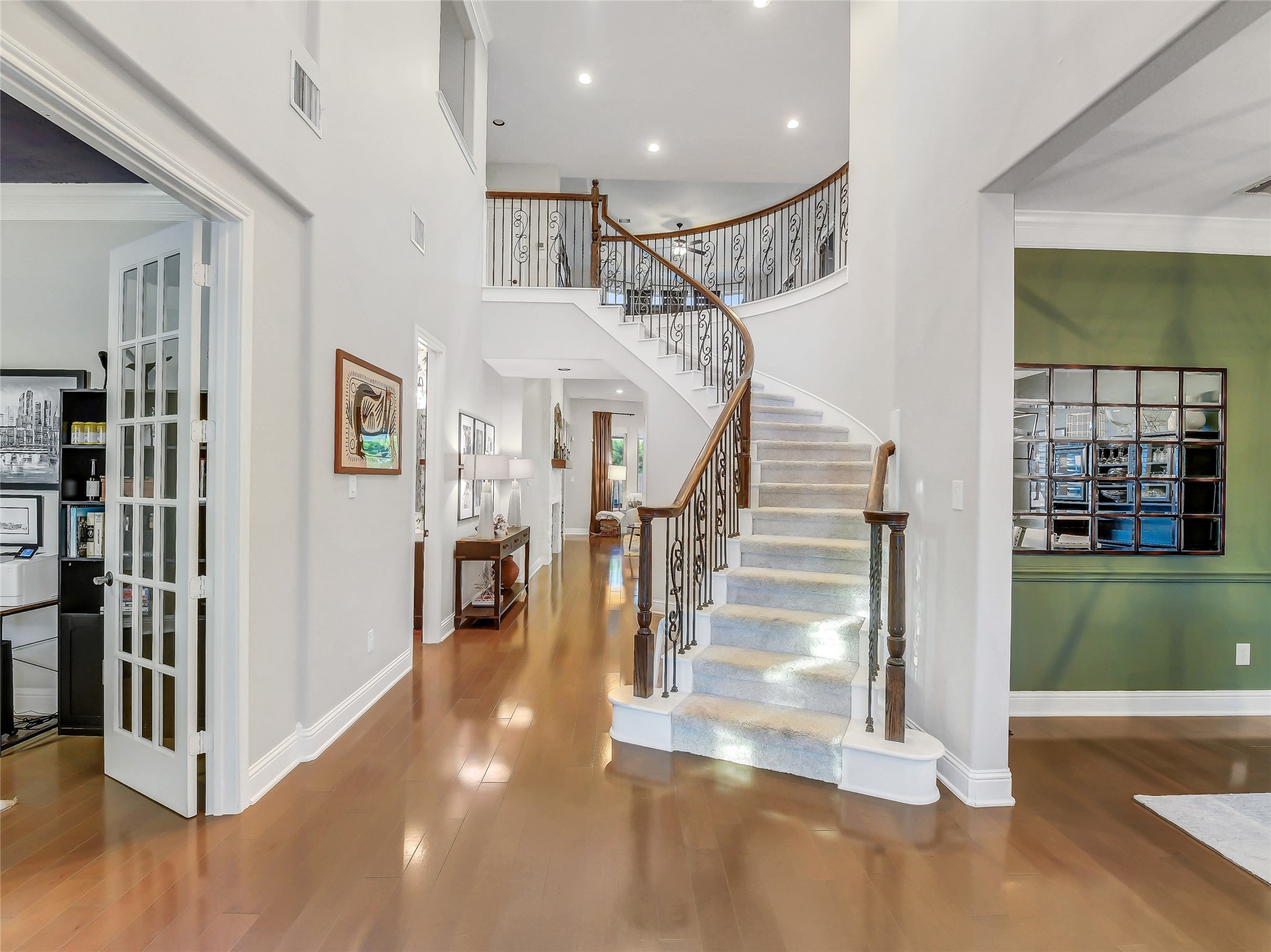 Enter through double doors to a grand entry with sweeping iron staircase. This elegant entry creates a stunning first impression while offering seamless access to the study, formal dining room, and main living areas.