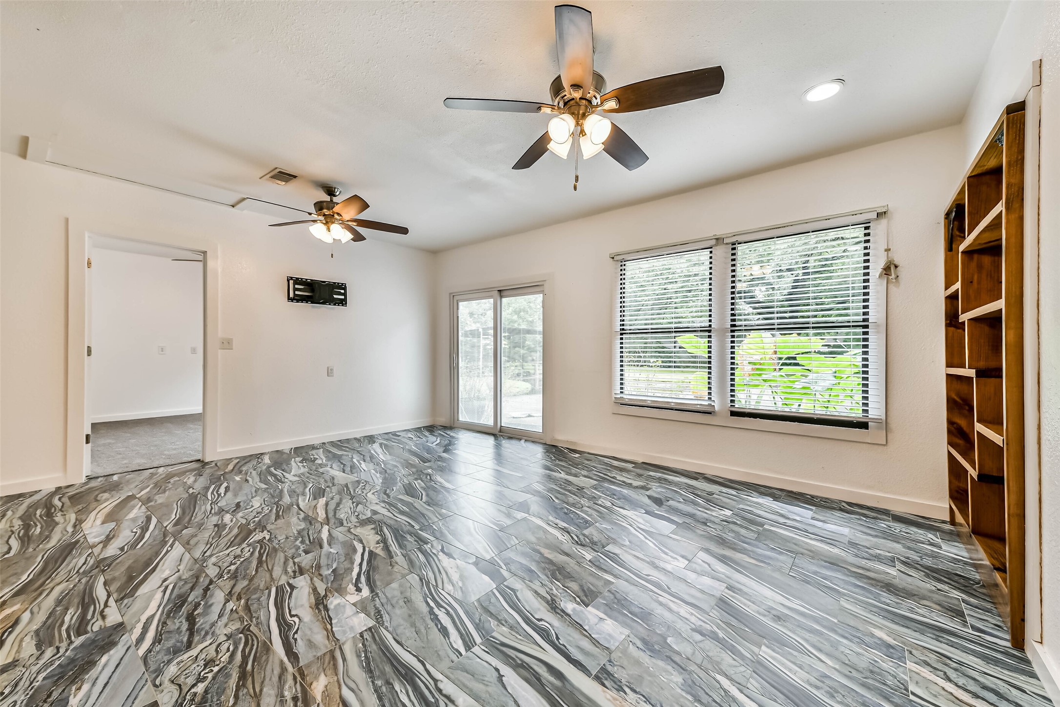 View of door to patio, built in shelving, door on left leads to 1st bedroom