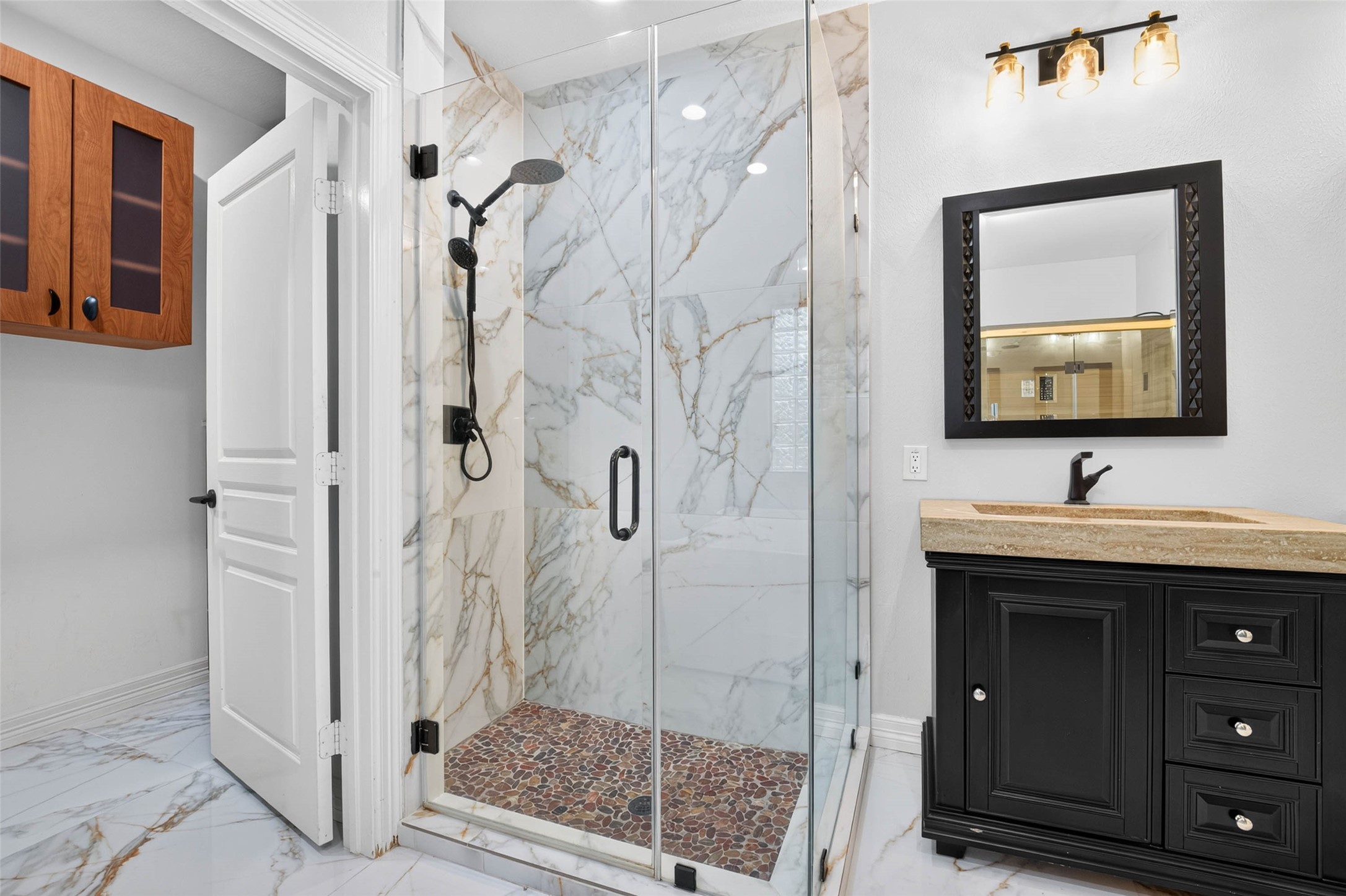 Separate remodeled shower with frameless glass shower door.
